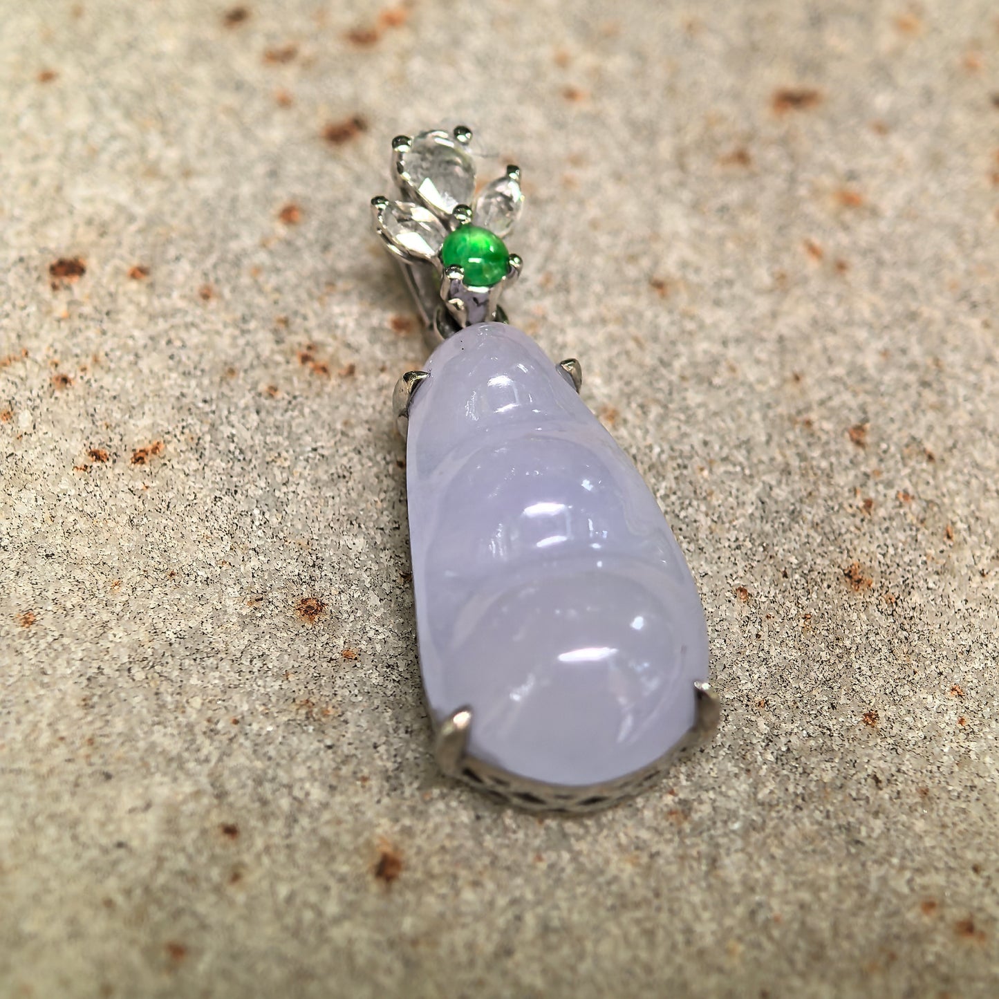 Close-up of violet bean jadeite pendant on stone background with polished surface and decorative 18K gold setting.