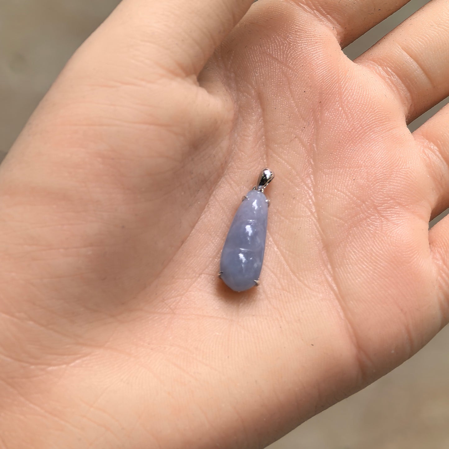 Handheld icy glutinous violet bean jadeite pendant showing small size, soft violet tone, and polished surface.