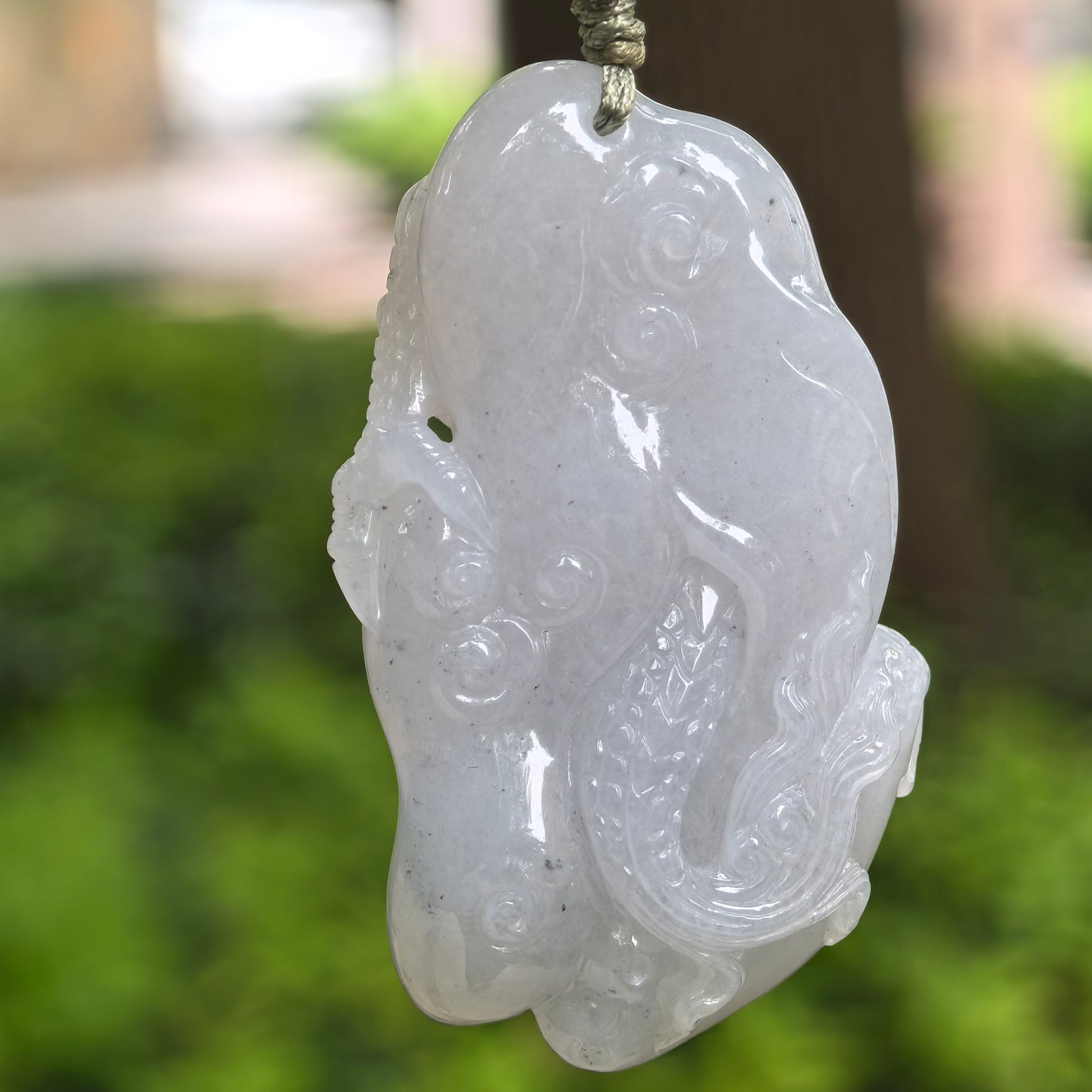 Back view of glutinous pale lavender-white dragon jadeite pendant showing smooth carved details and soft luster.
