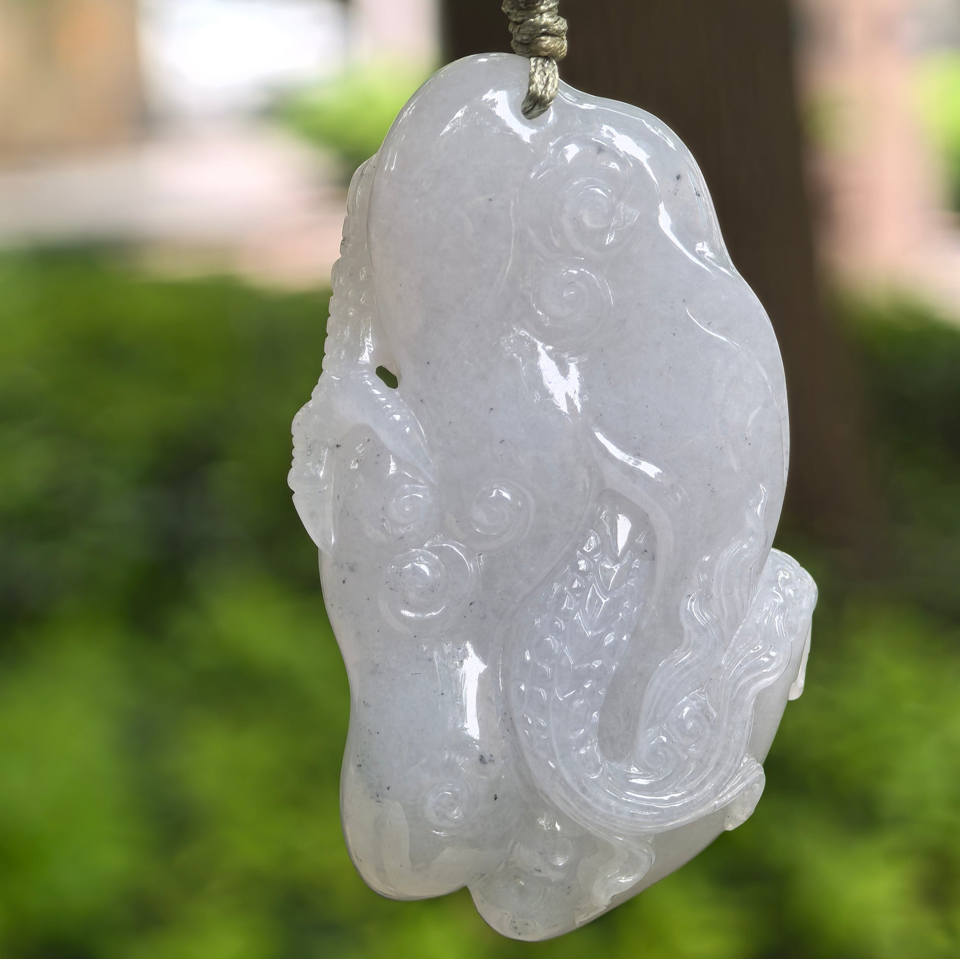 Back view of glutinous pale lavender-white dragon jadeite pendant showing smooth carved details and soft luster.
