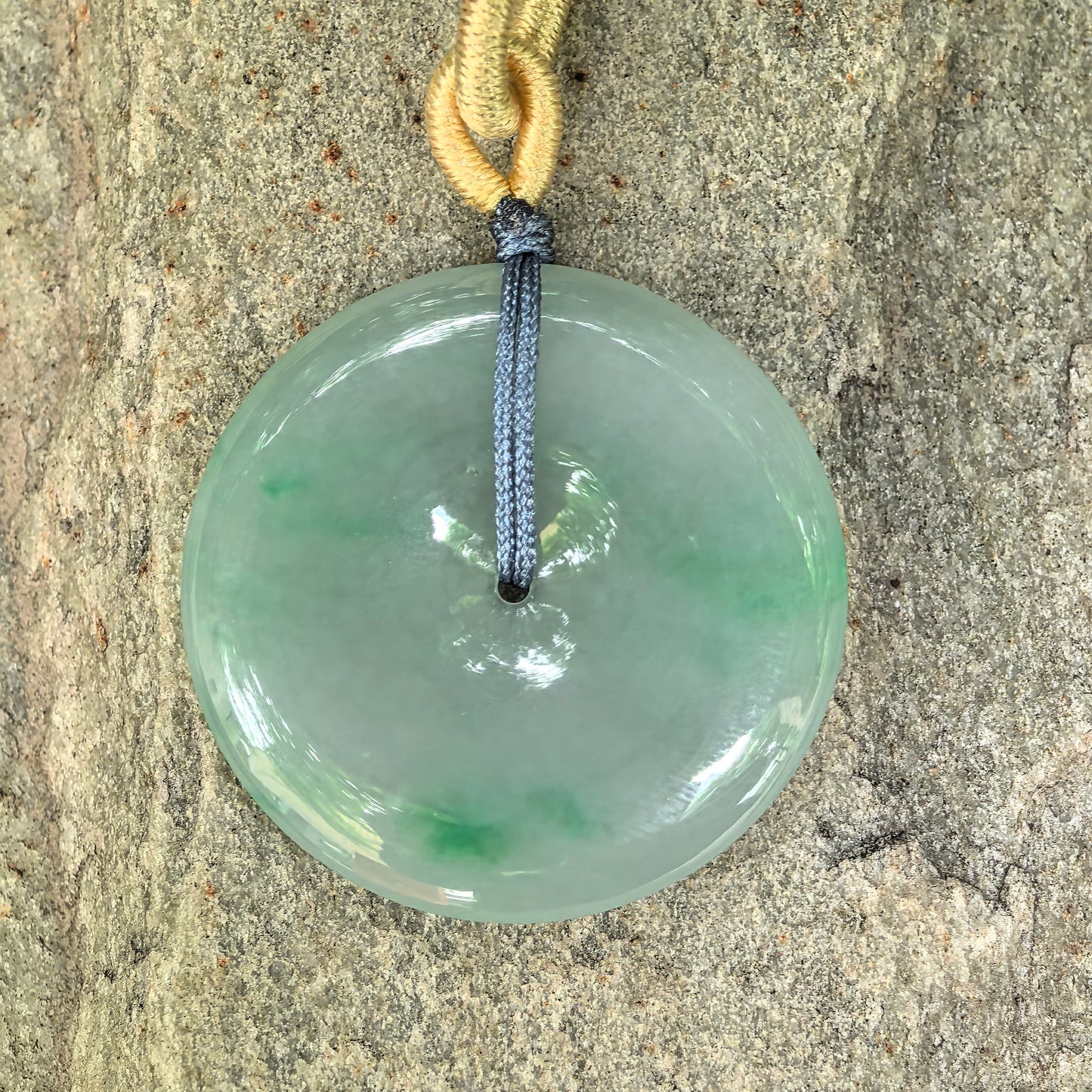 Close-up of fine glutinous green Peace Pendant jadeite pendant on stone background with delicate texture and polished luster.