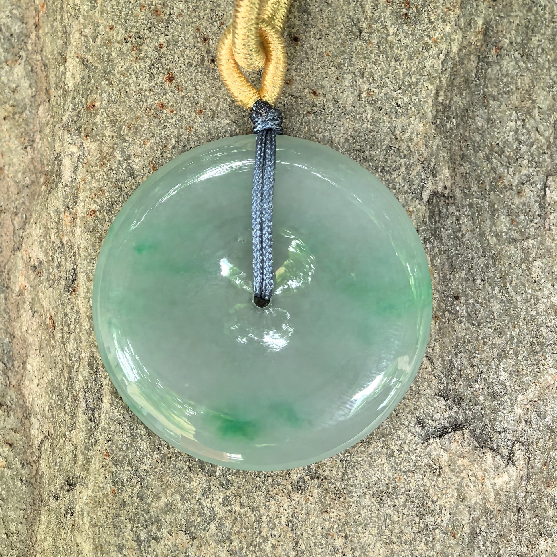Close-up of fine glutinous green Peace Pendant jadeite pendant on stone background with delicate texture and polished luster.
