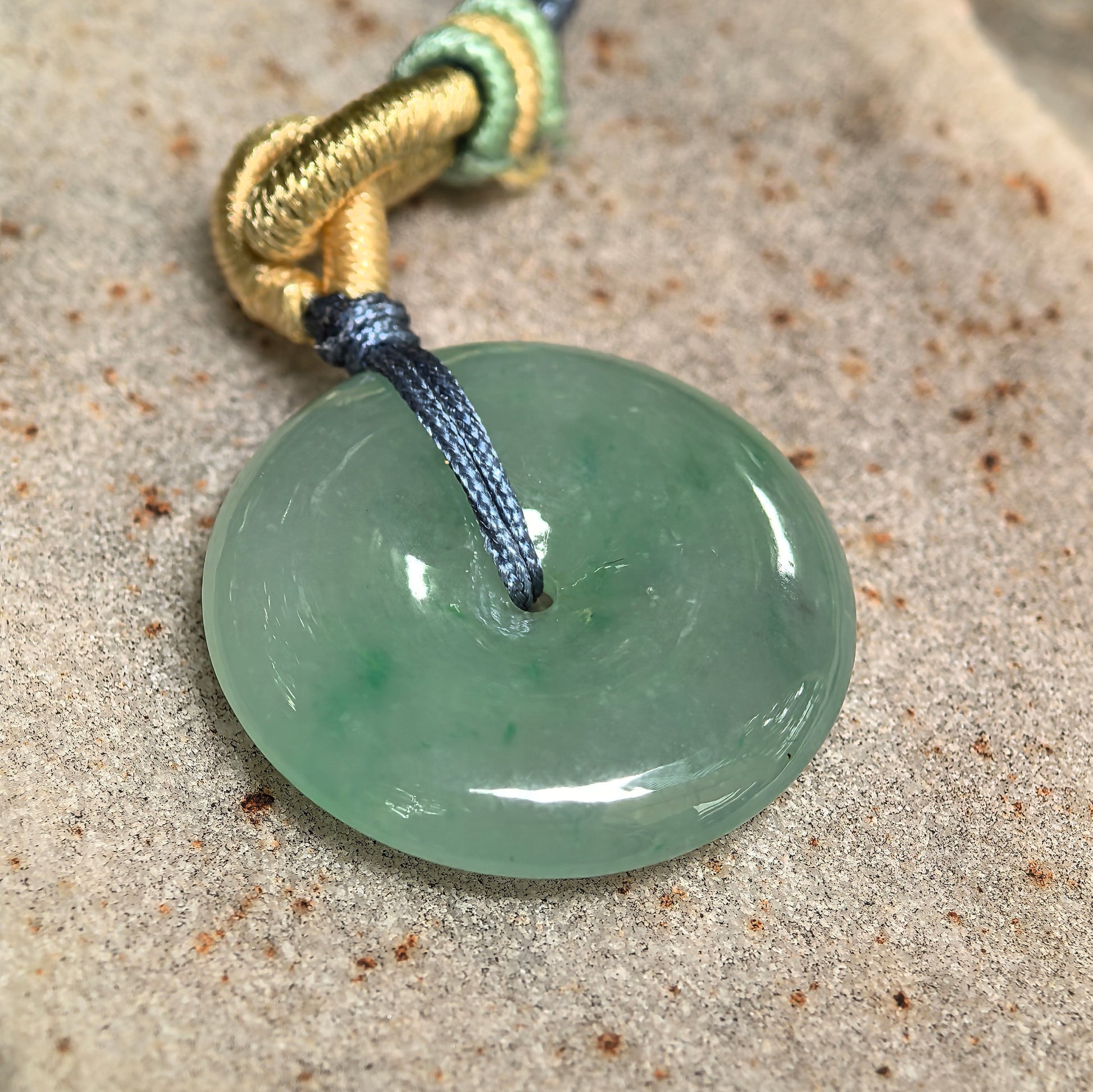 Close-up of Natural Grade-A green Peace Pendant jadeite pendant on stone background with gel-like luster.