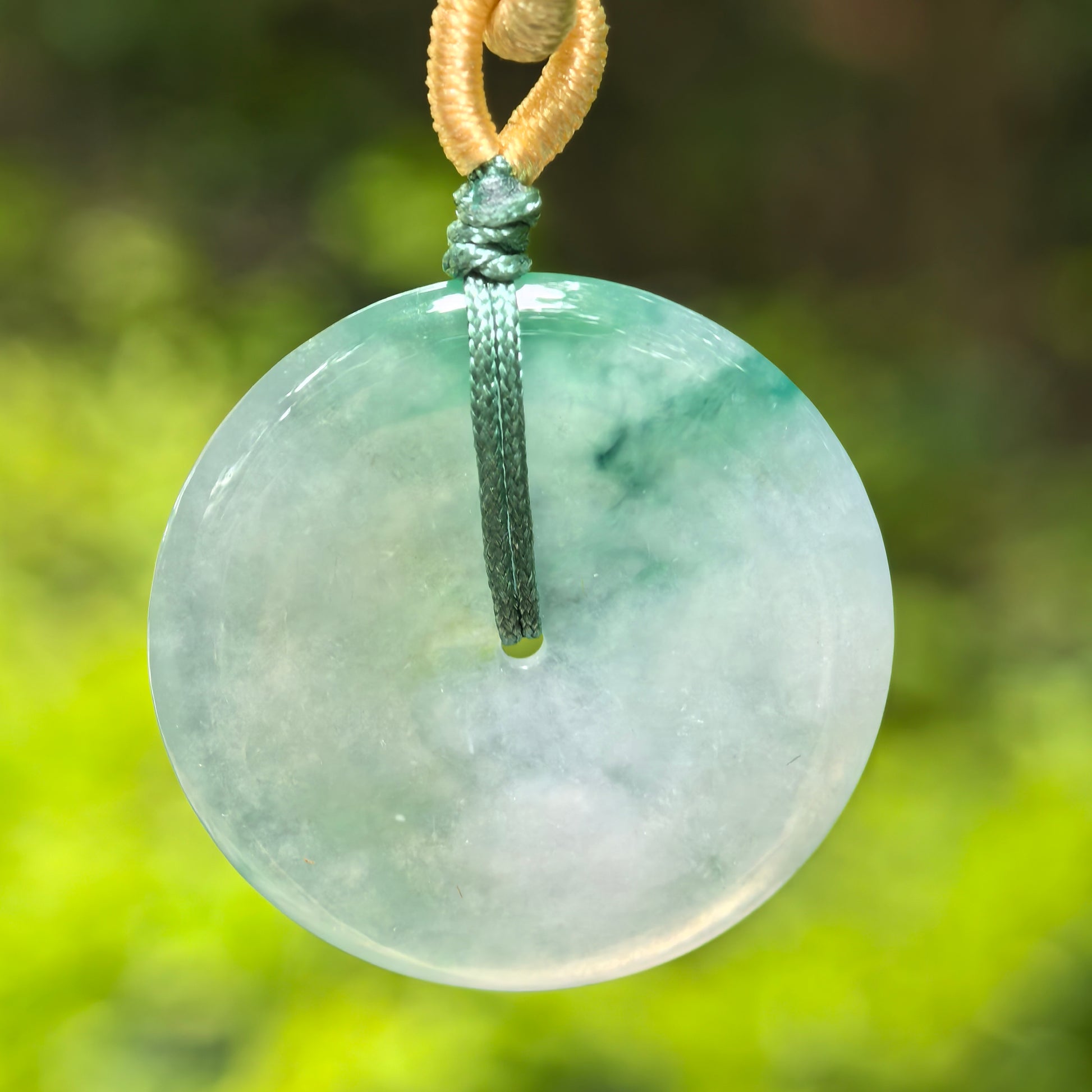 Natural Grade-A icy glutinous floating green Peace Buckle jadeite pendant hanging outdoors with cord.