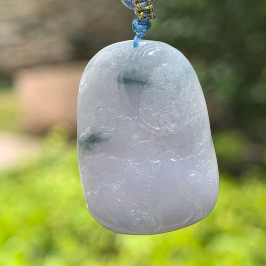 Natural Grade-A glutinous lavender landscape jadeite pendant hanging with cord against an outdoor background.