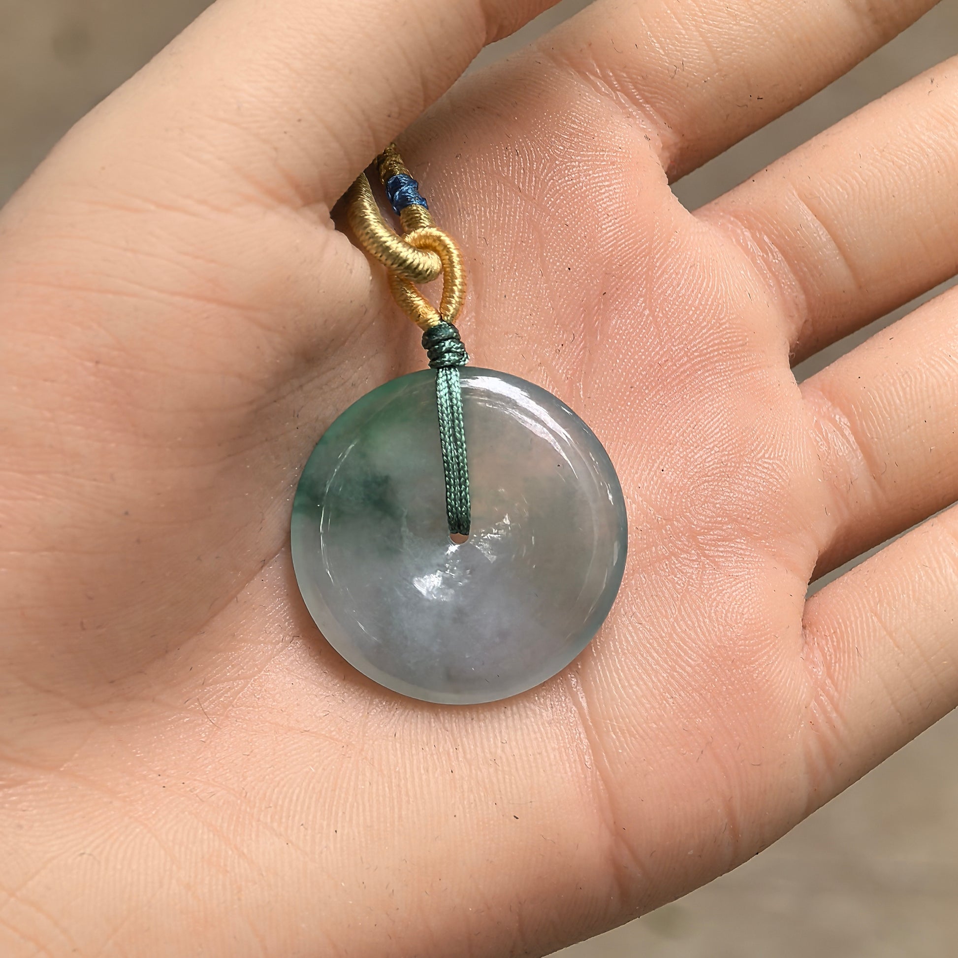 Handheld Natural Grade-A floating green jadeite Peace Buckle pendant showing compact size and central opening.