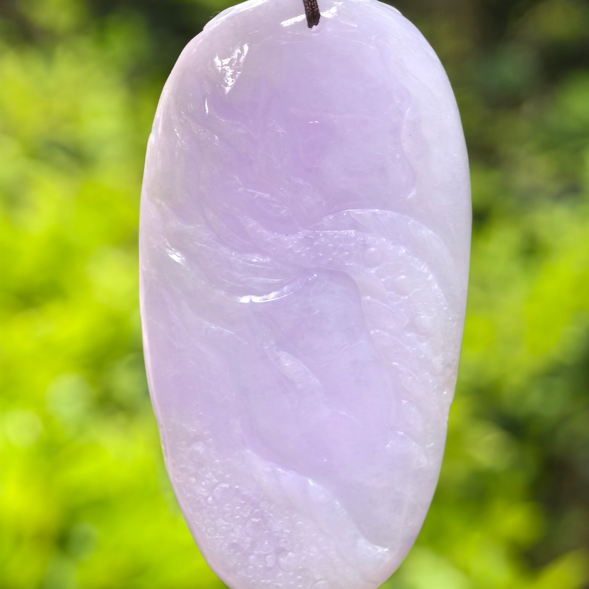 Back view of a light purple jadeite dragon pendant showing the polished surface and carving details.
