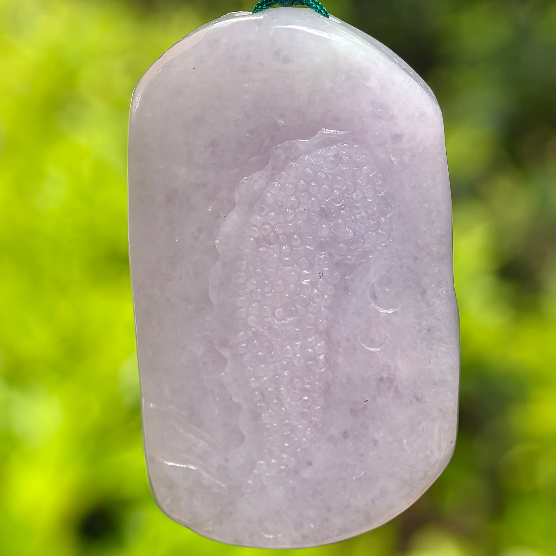 Back view of a light purple jadeite dragon pendant with smooth polished surface.