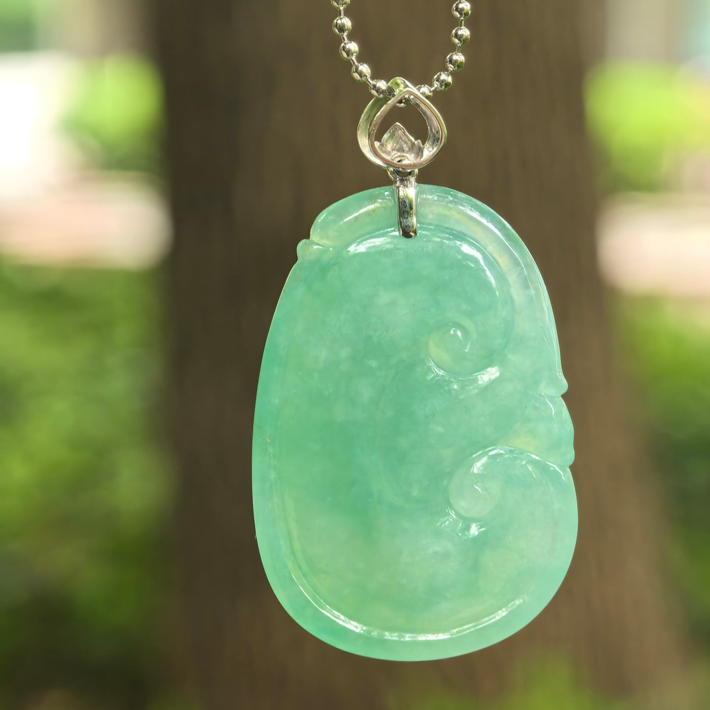 Back view of fruit green Ruyi jadeite pendant showing smooth carving and soft translucency.