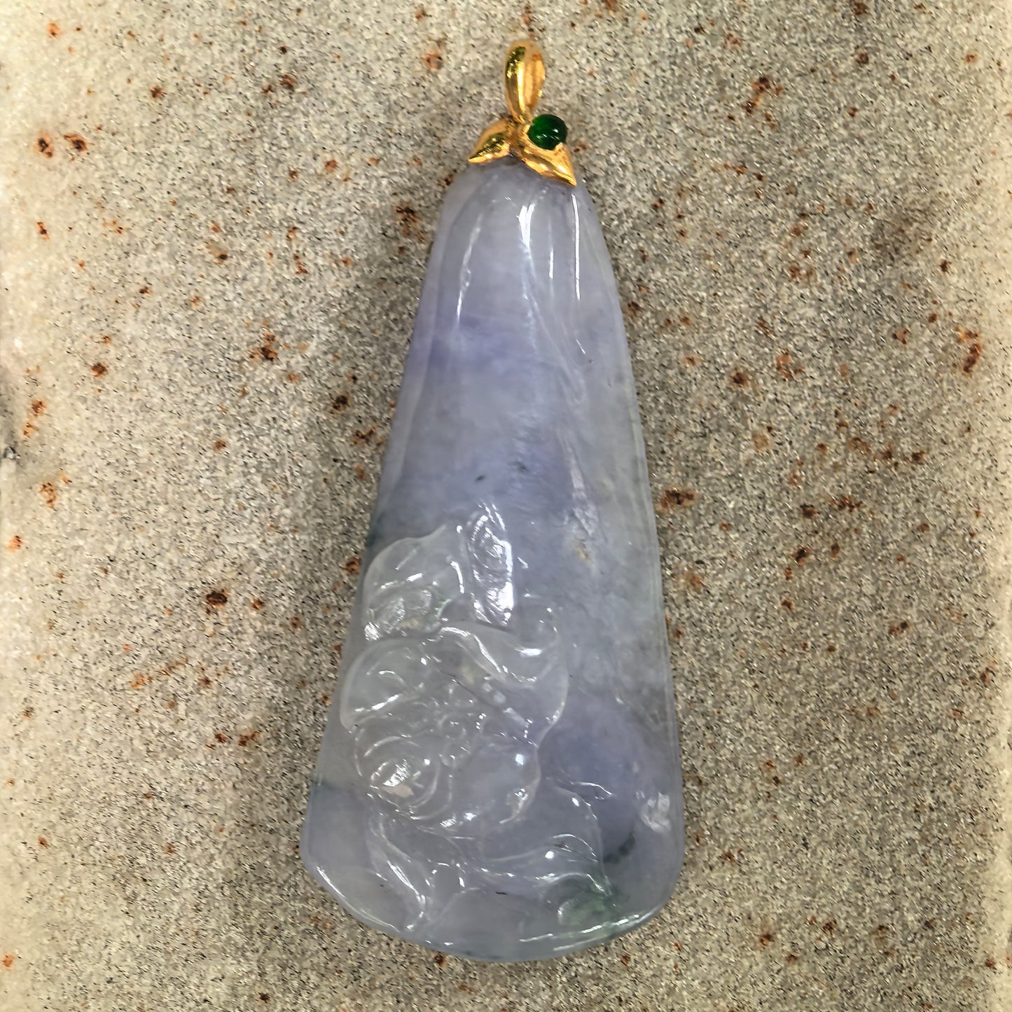 Close-up of icy glutinous blue-lavender lotus jadeite pendant on stone background with carved lower lotus detail.
