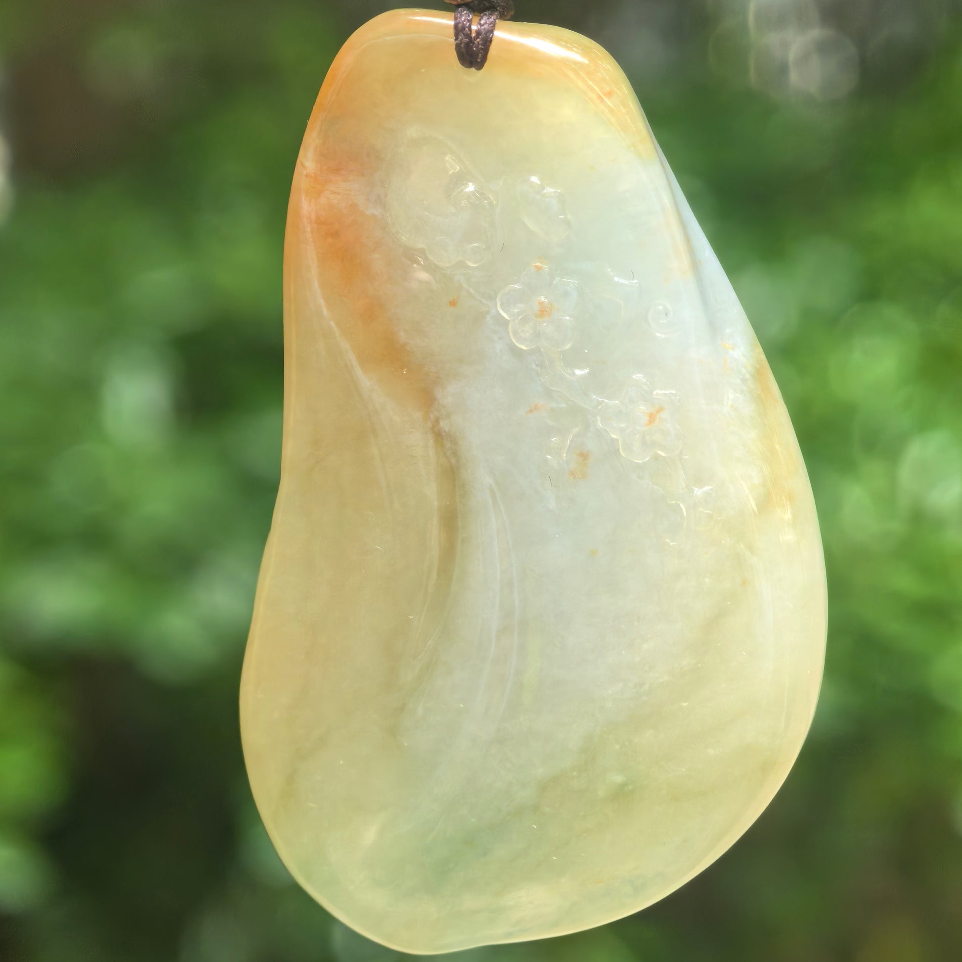 Back view of carved yellow-green jadeite deer pendant showing smooth polished surface and warm tone.

