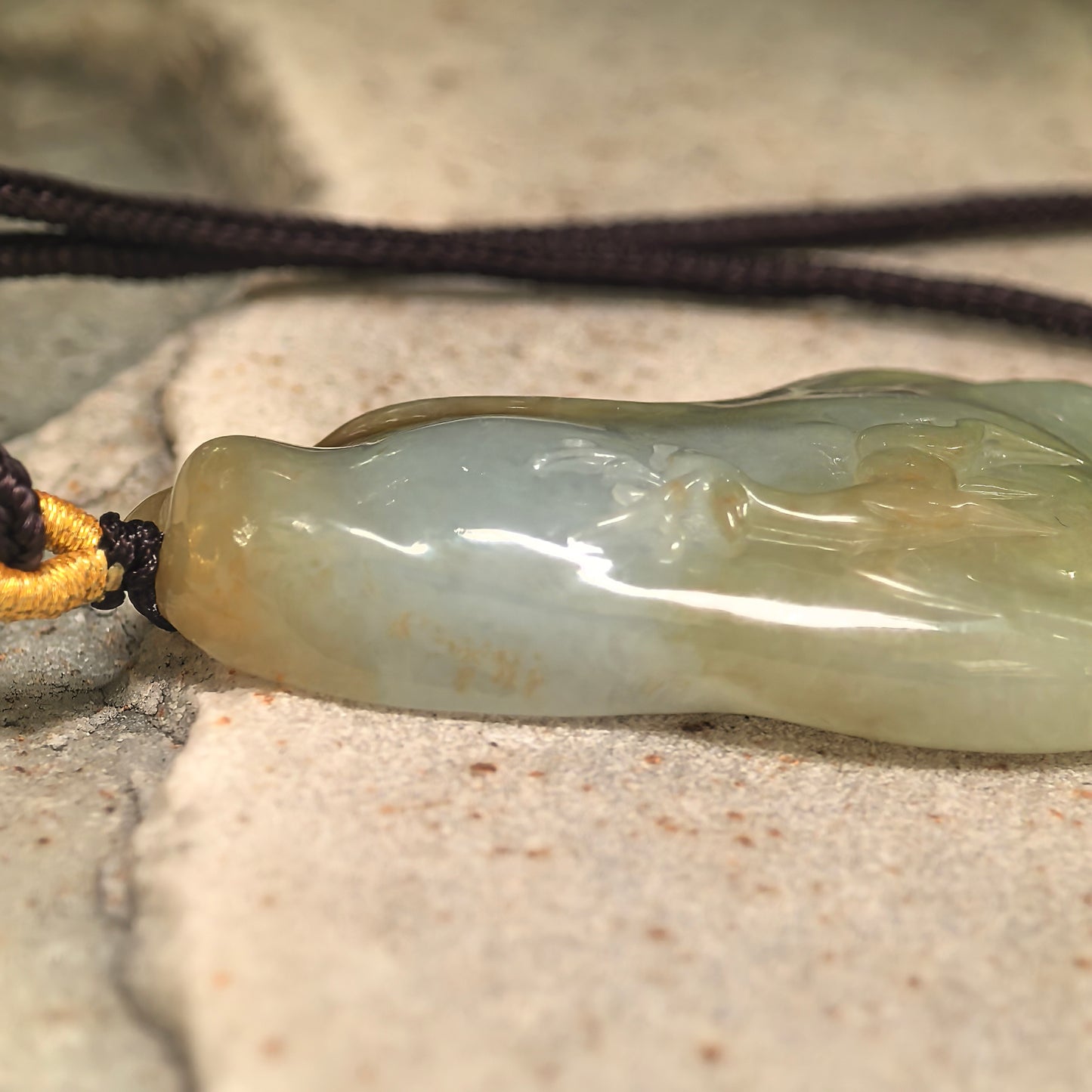 Side view of glutinous deer jadeite pendant showing thickness, curved form, and polished luster.