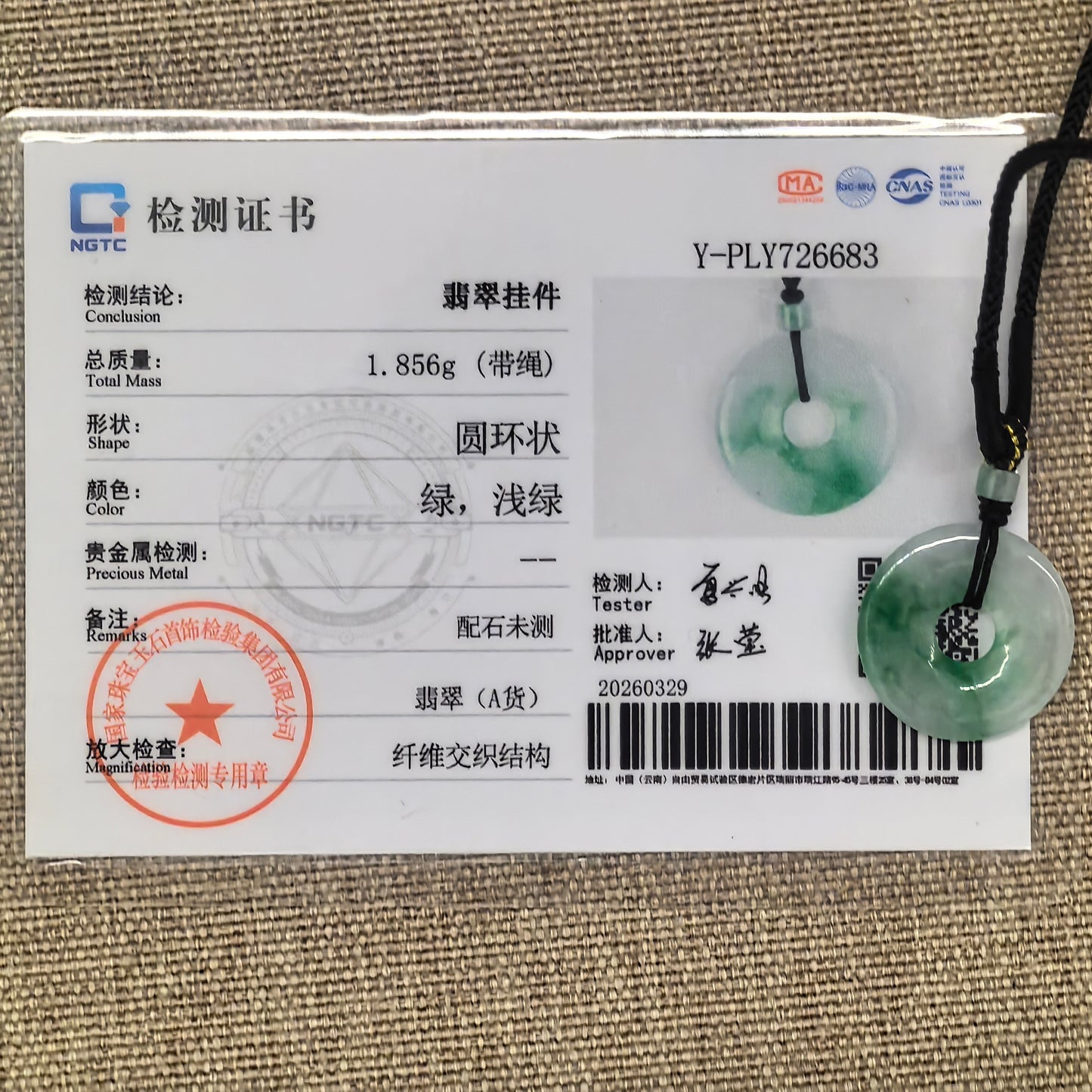 NGTC certified white-based green donut jadeite pendant shown with matching certificate and cord.