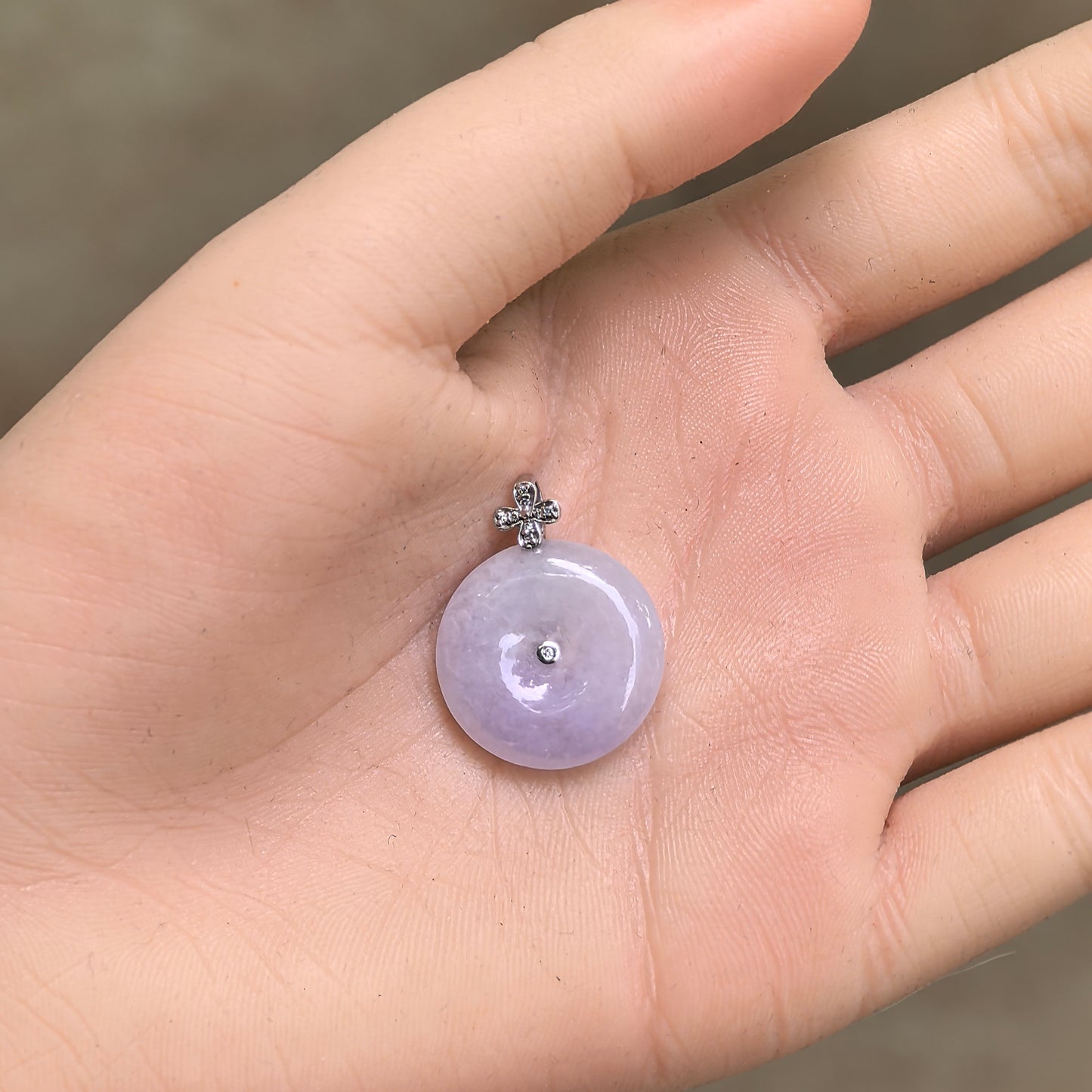 Hand-held light lavender jadeite Peace Pendant showing polished circular shape and soft glutinous texture.
