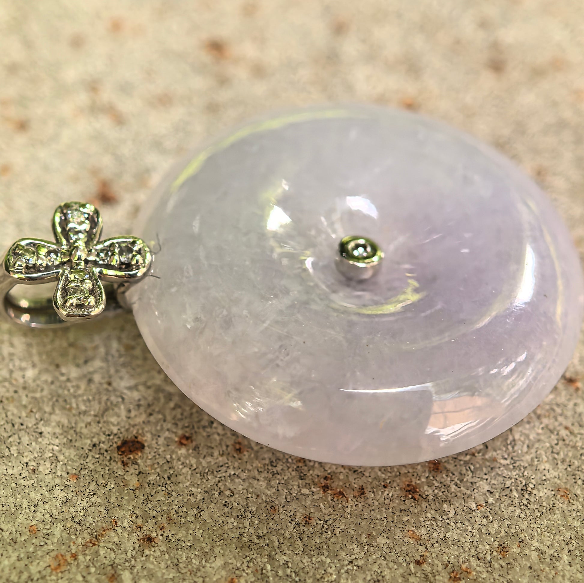 Close-up of light lavender jadeite Peace Pendant with diamond-accented 18K gold floral bail.
