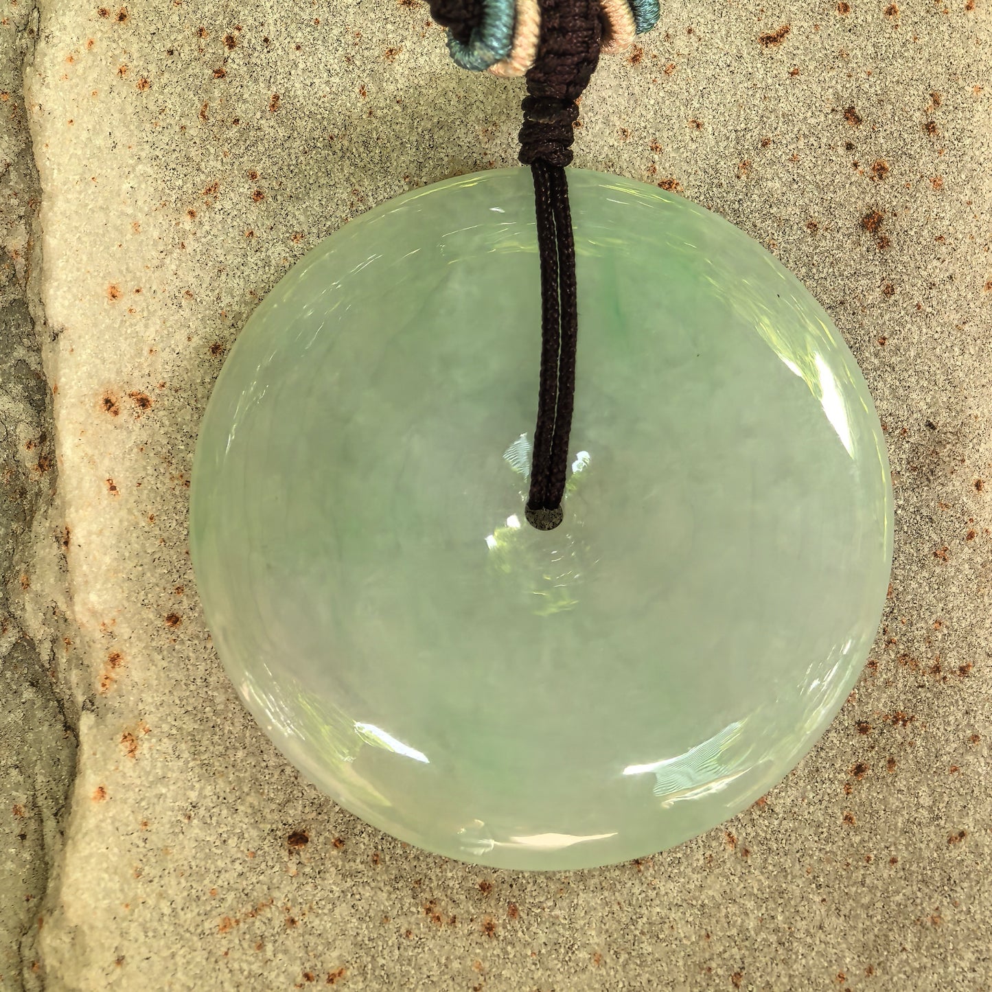 Close-up of glutinous light green jadeite Peace Pendant with smooth polished surface.

