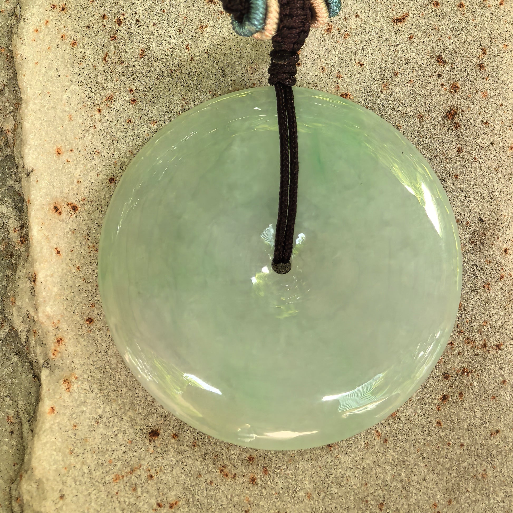 Close-up of glutinous light green jadeite Peace Pendant with smooth polished surface.
