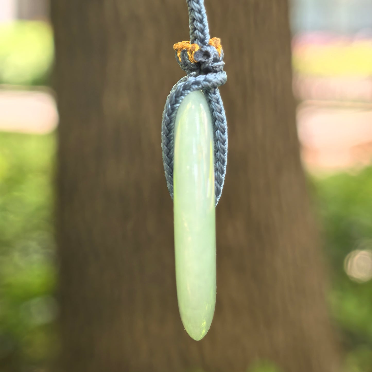 Side view of pale green glutinous jadeite Peace Pendant showing polished thickness and smooth surface.
