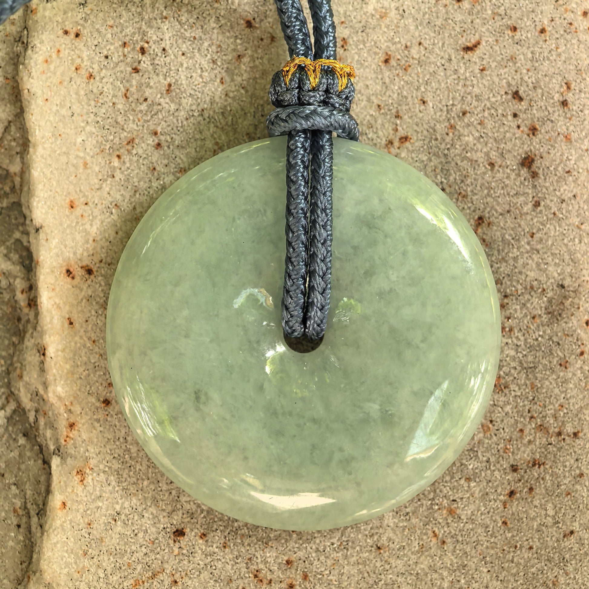 Close-up of circular pale green jadeite Peace Pendant with soft luster and central opening.
