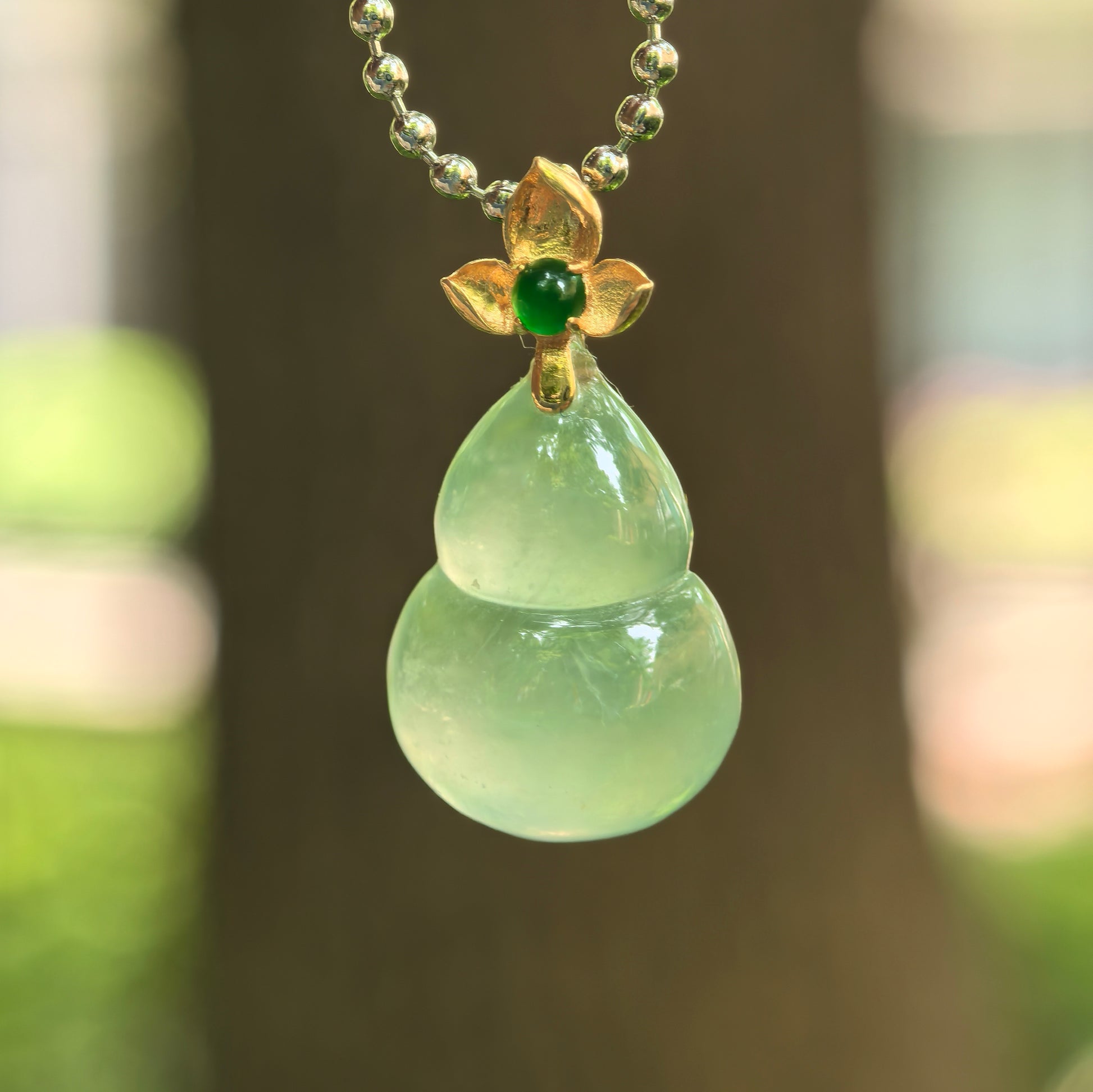 Natural Grade-A icy light green gourd jadeite pendant with 18K gold floral bail.
