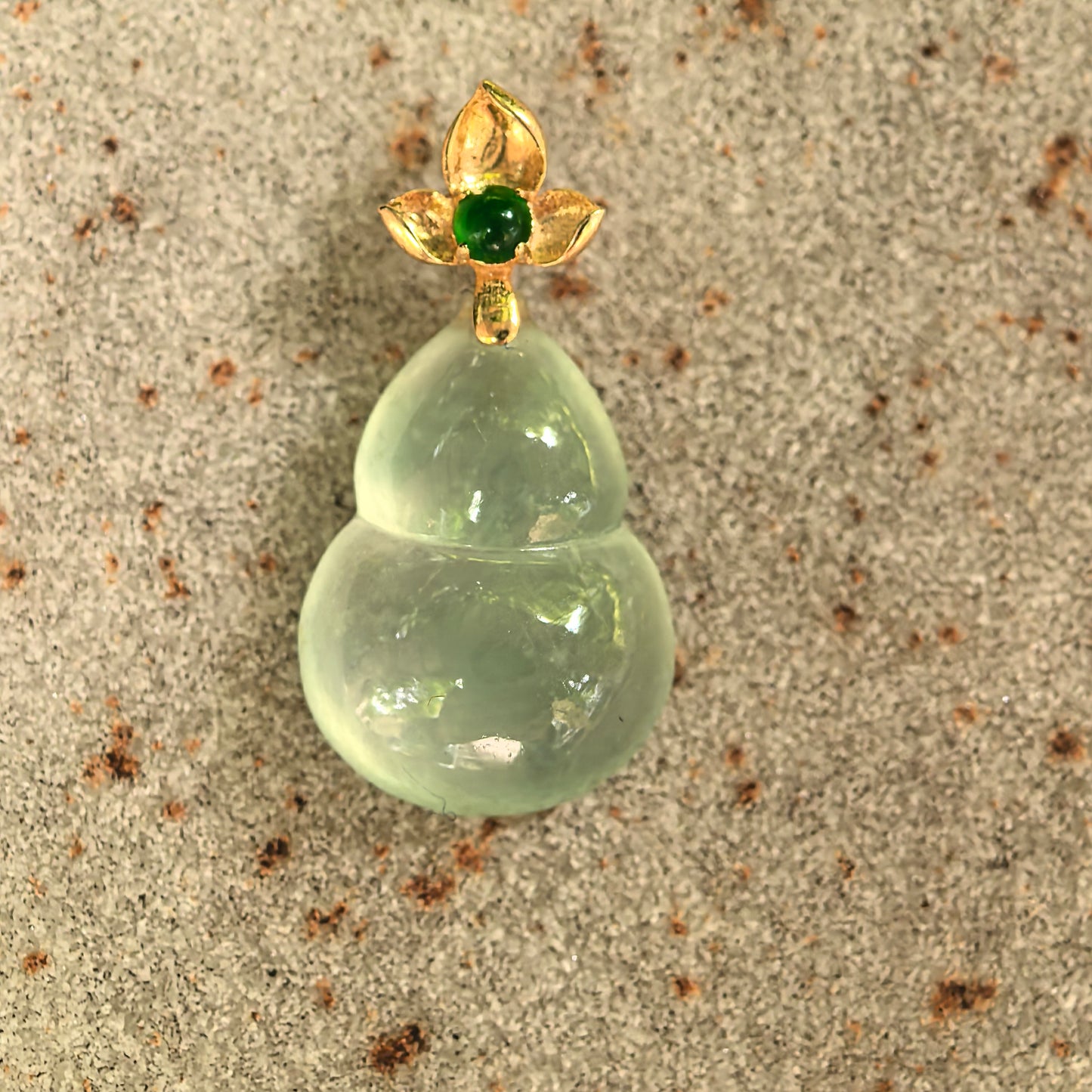 Close-up of light green gourd jadeite pendant showing icy translucency and polished surface.
