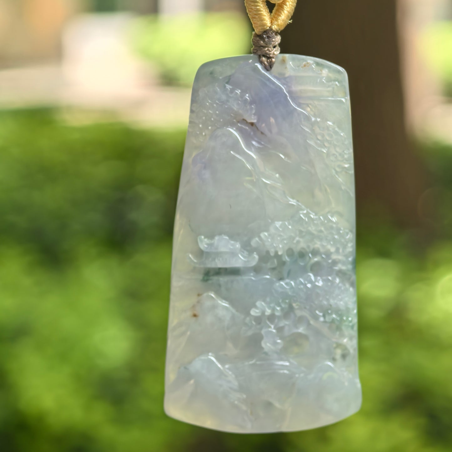 Natural Grade-A icy glutinous purple landscape plaque jadeite pendant hanging on a handwoven cord.
