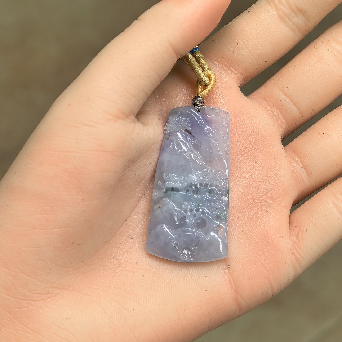 Natural Grade-A purple landscape jadeite pendant shown in hand for size reference.
