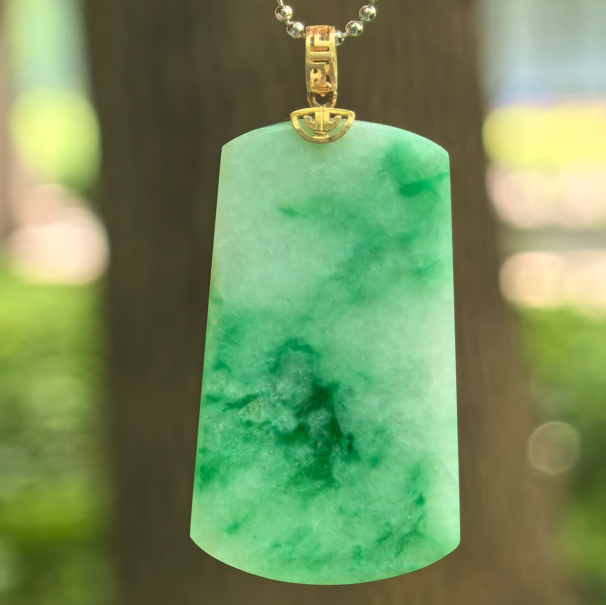 Natural Grade-A glutinous light green plain jade plaque pendant with floating green patterns and 18K gold bail.
