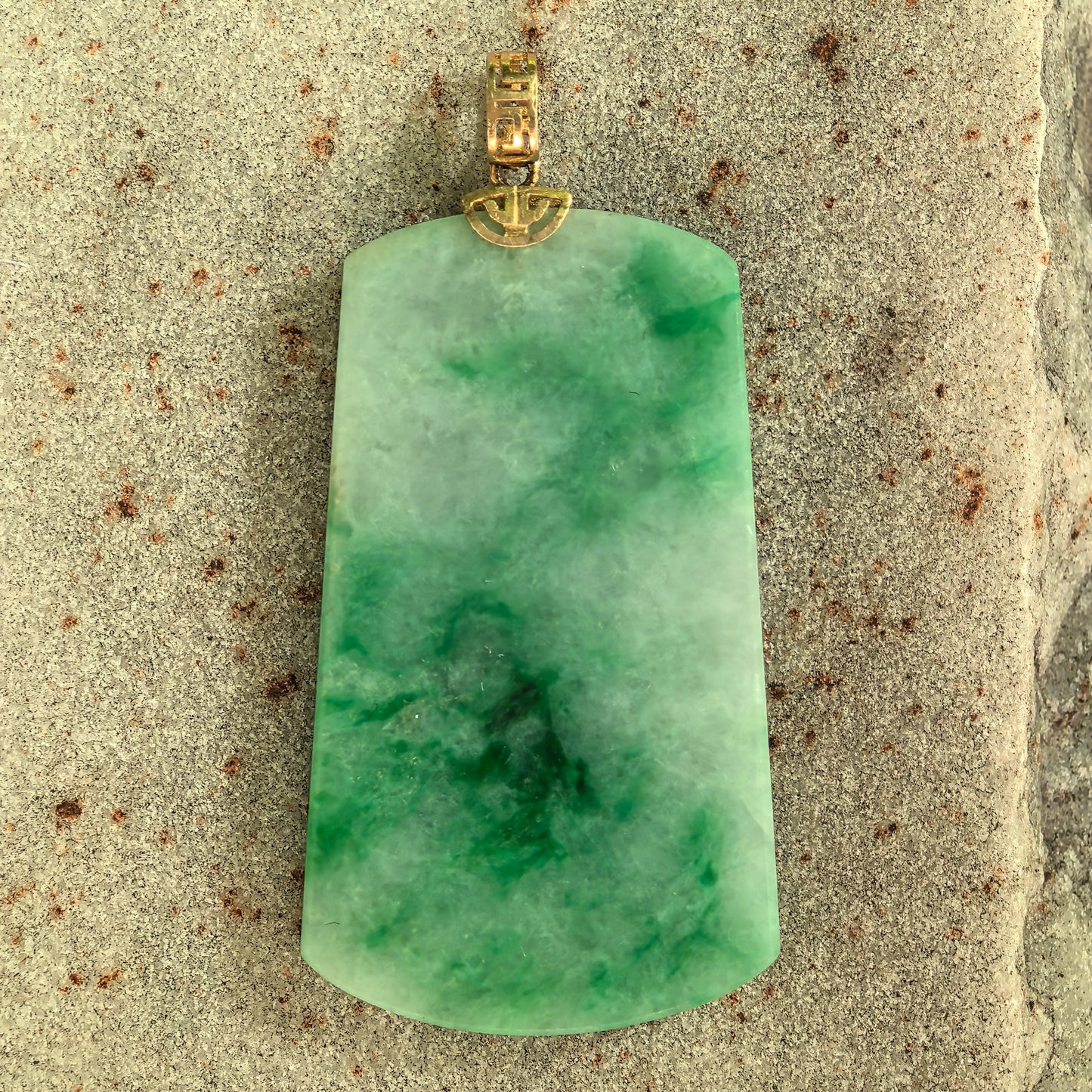 Close-up of glutinous light green jadeite plain plaque pendant showing floating green patterns.
