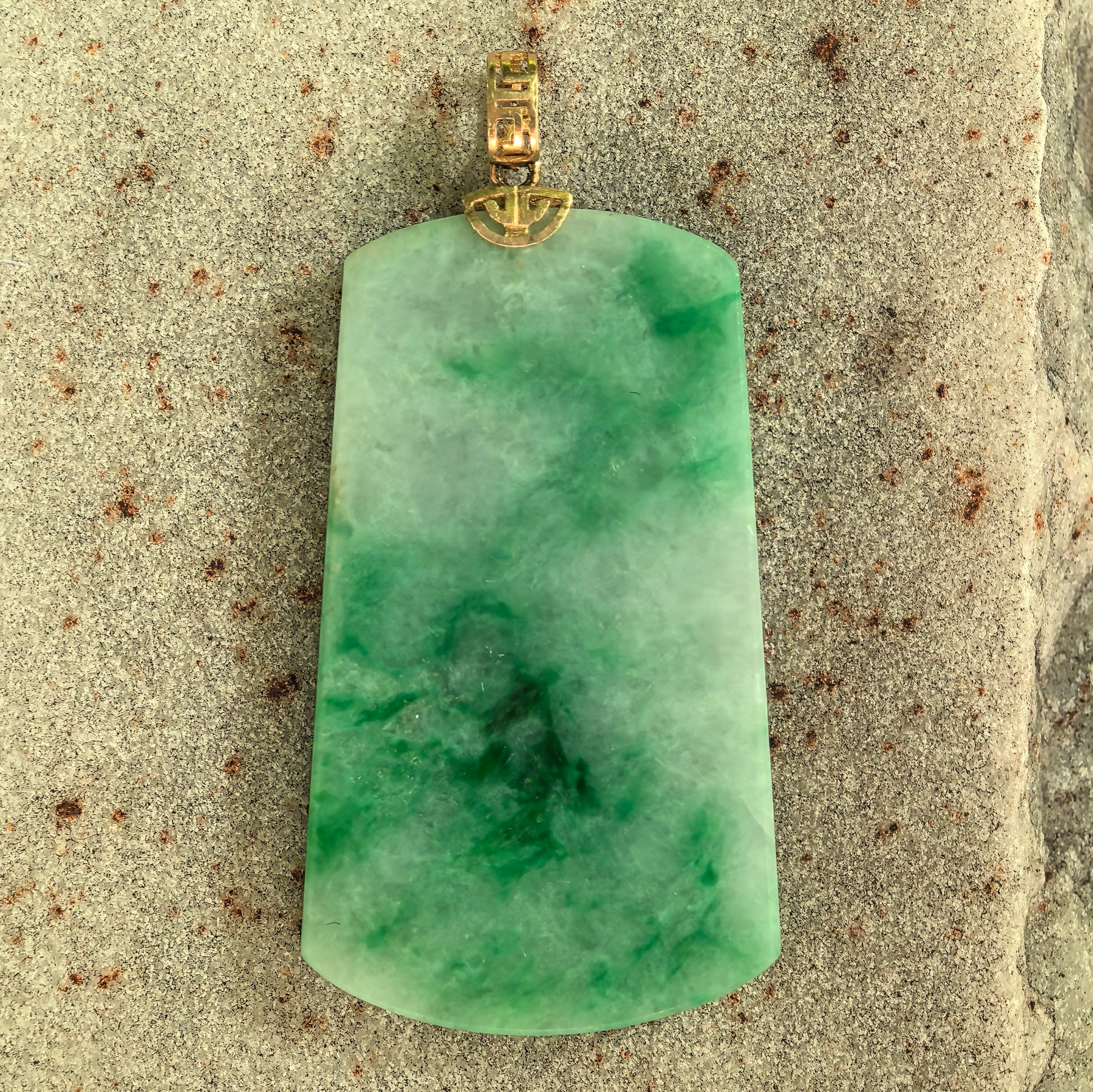 Close-up of glutinous light green jadeite plain plaque pendant showing floating green patterns.
