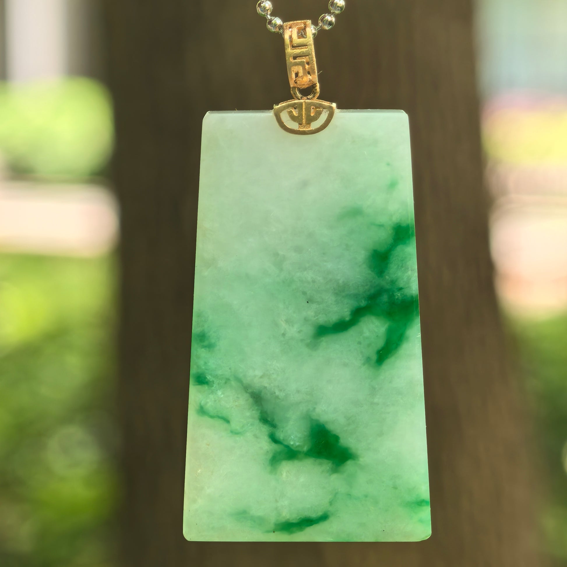 Natural Grade-A glutinous light green plain jade plaque pendant with floating green patterns and 18K gold bail.
