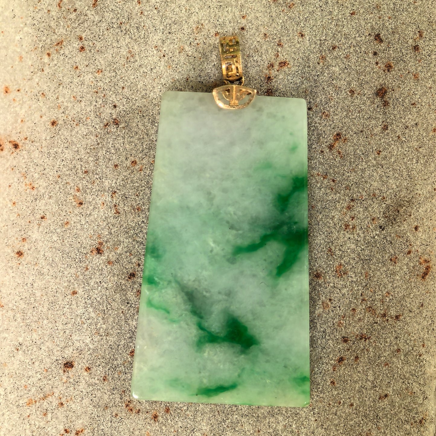 Close-up of glutinous jadeite plain plaque pendant showing polished surface and green texture.
