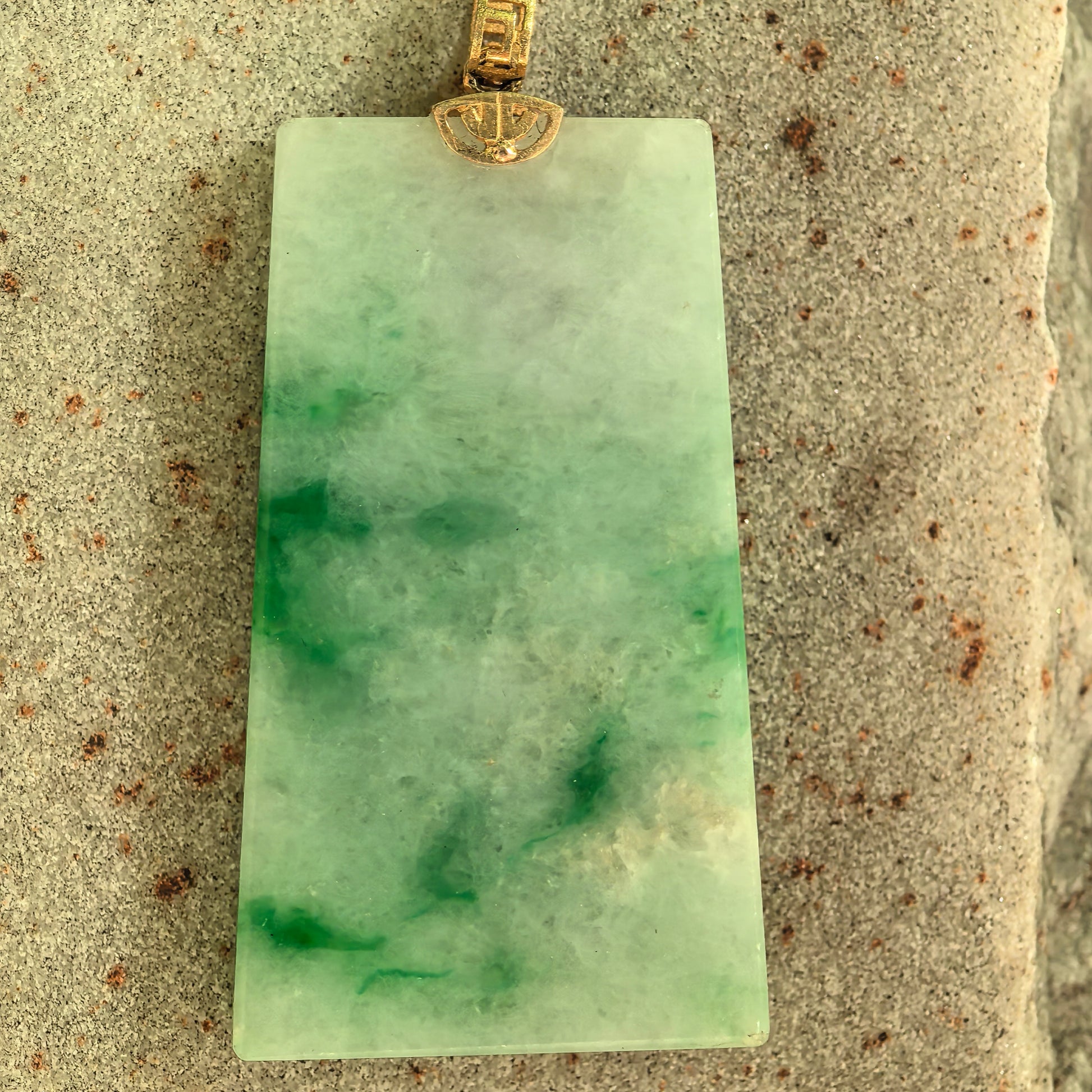 Back view of light green jadeite plain plaque pendant showing obvious visible surface cotton.
