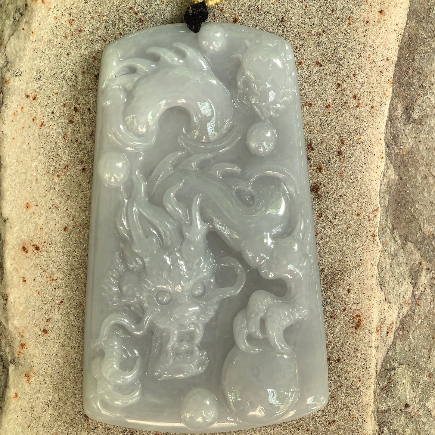 Close-up of fine glutinous dragon jadeite plaque showing raised carving and natural cotton texture.
