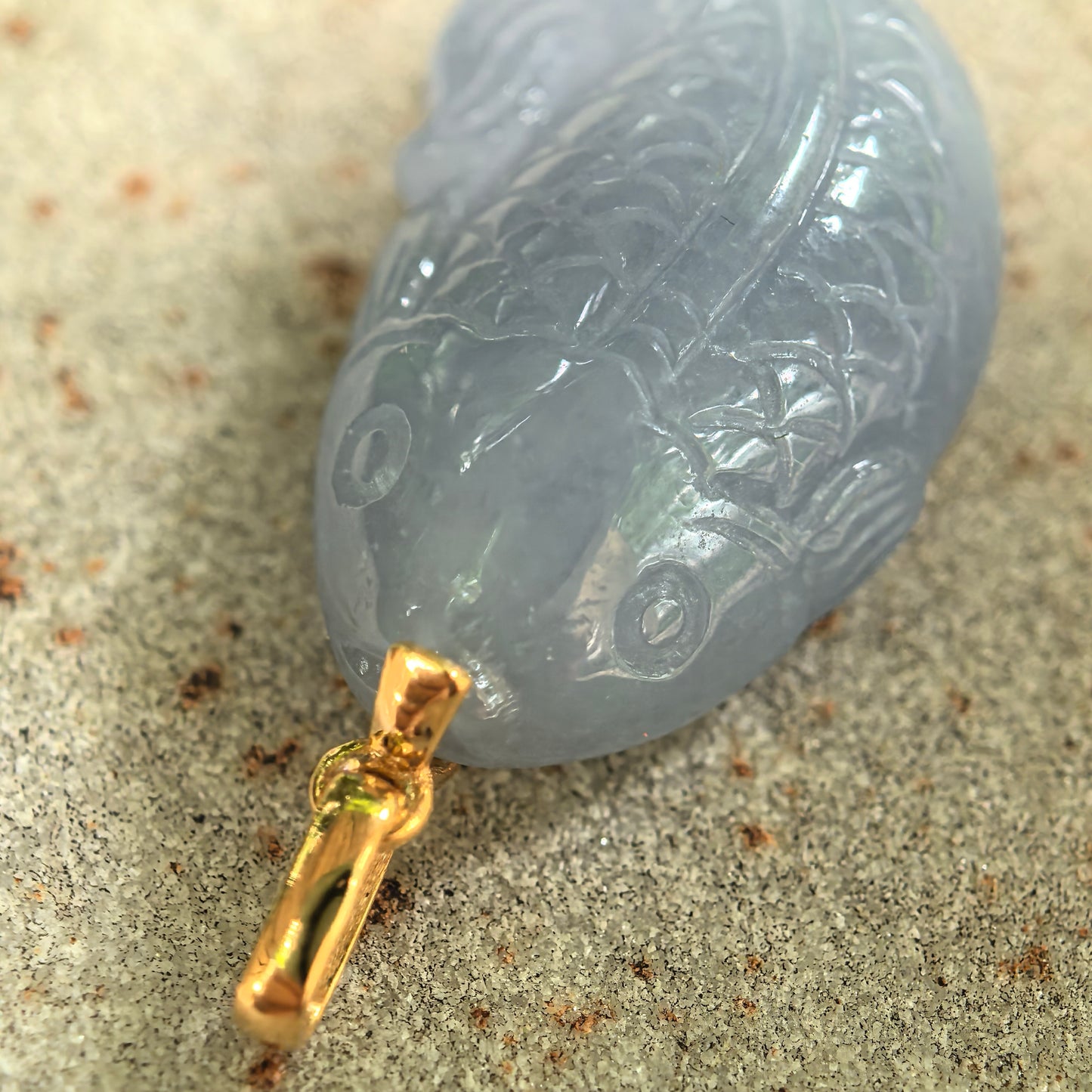 Close-up of lavender fish jadeite pendant showing carved scales, fin, and polished luster.
