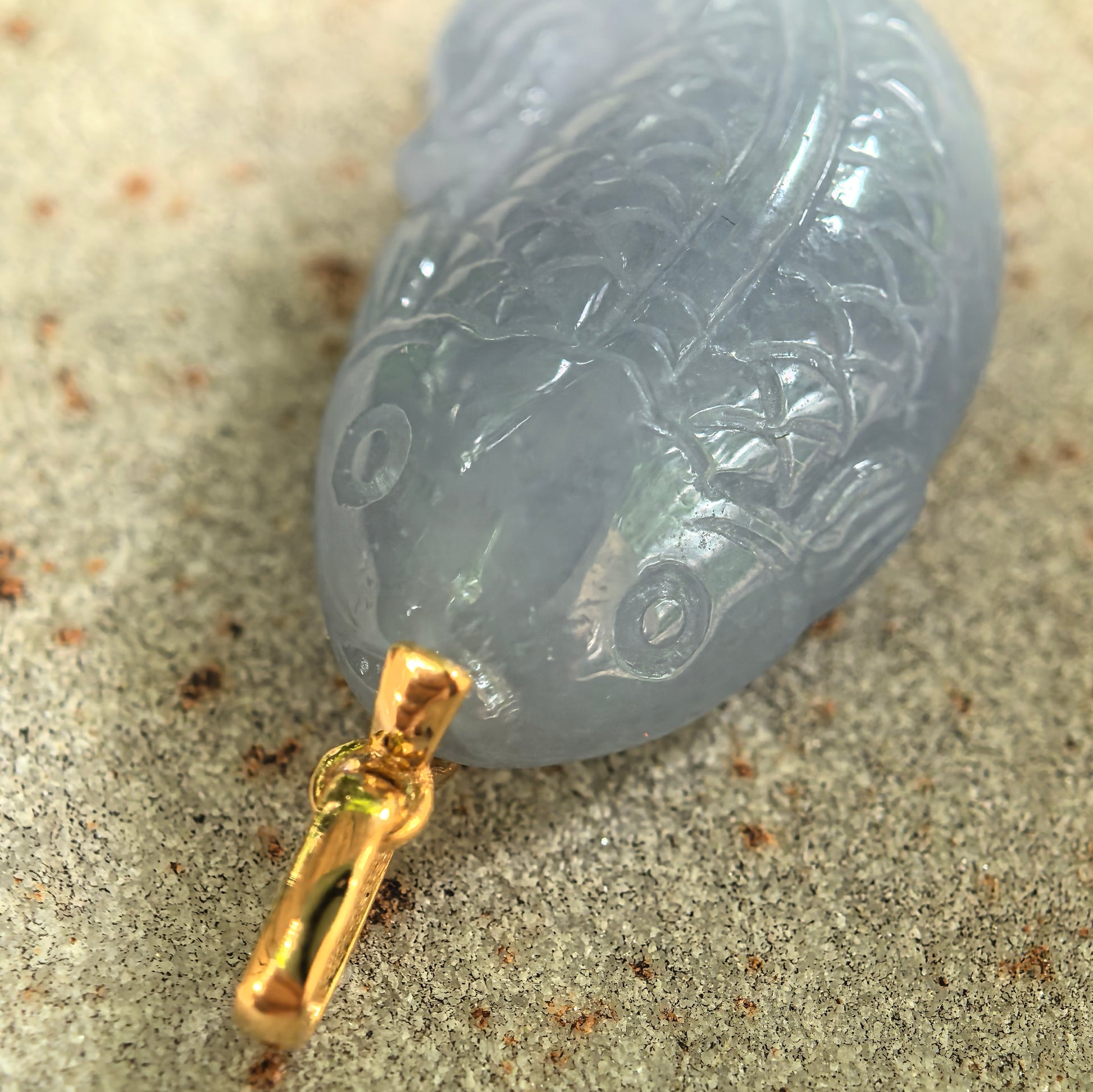 Close-up of lavender fish jadeite pendant showing carved scales, fin, and polished luster.
