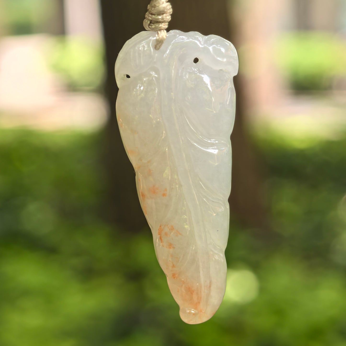 Natural Grade-A icy glutinous white-base golden-splash jadeite leaf pendant hanging on cord.
