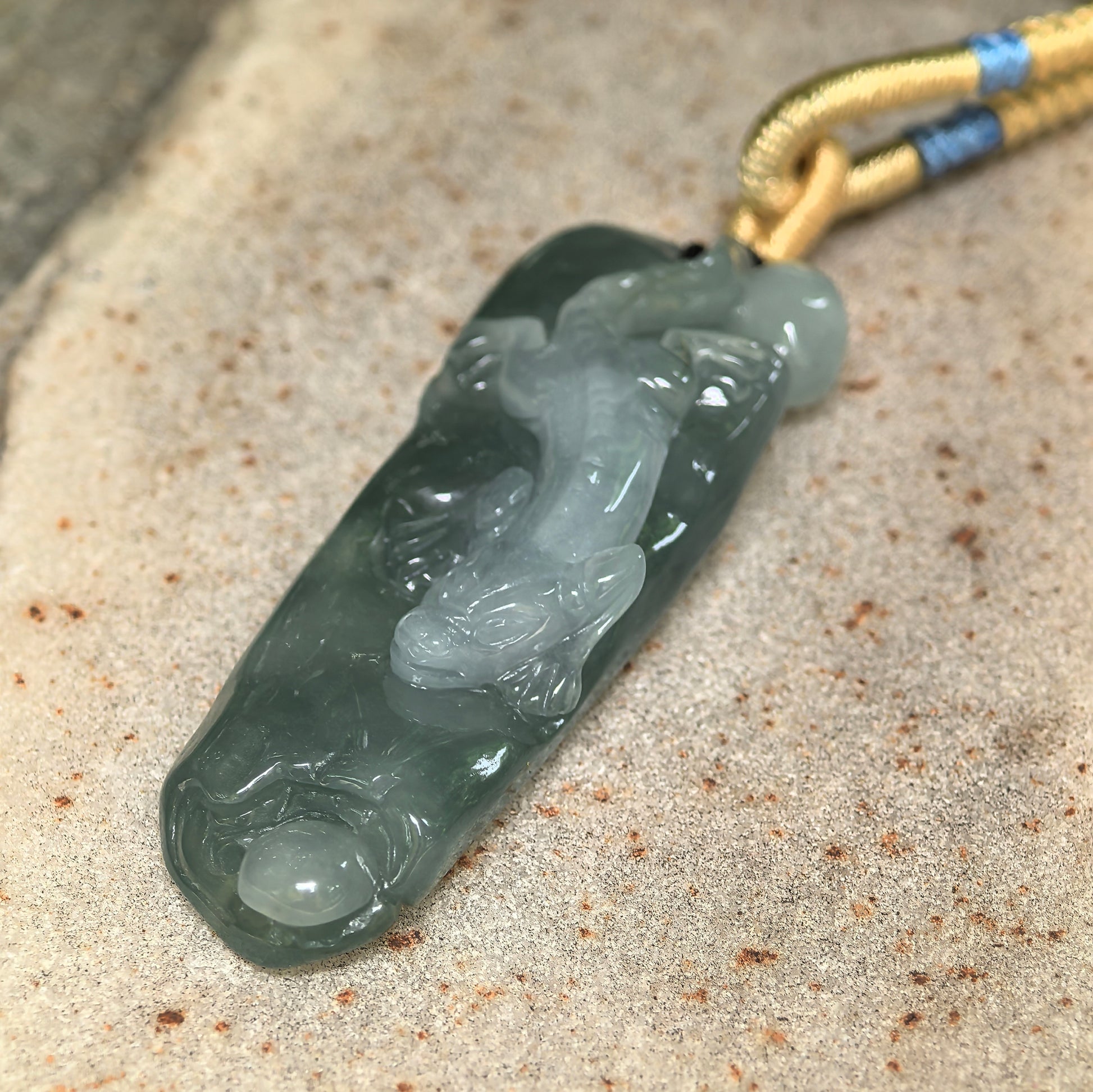 Close-up of icy glutinous oil green chi-dragon jadeite pendant showing raised carving and smooth luster.
