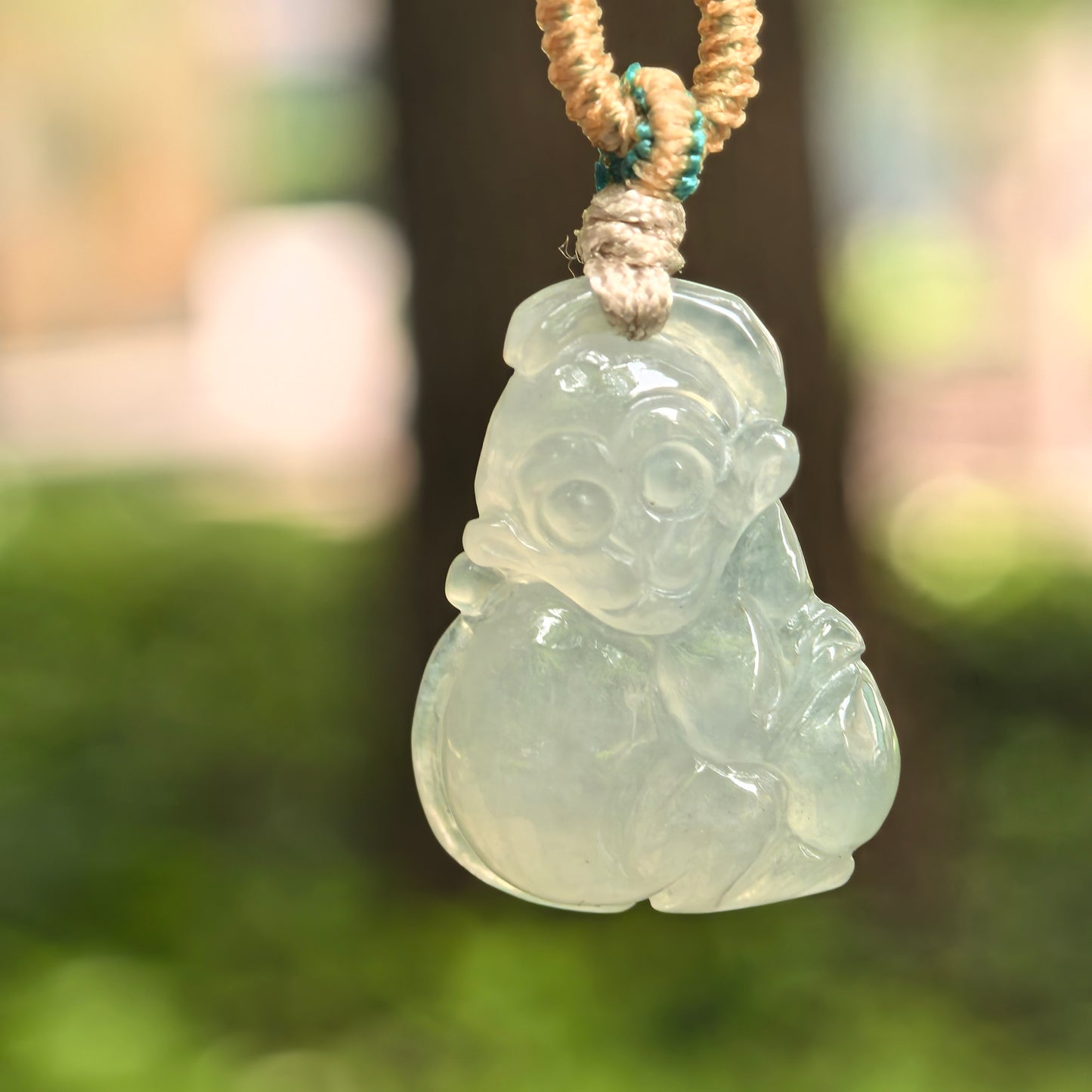 Natural Grade-A icy glutinous light green monkey jadeite pendant hanging on cord with soft icy-gel translucency.
