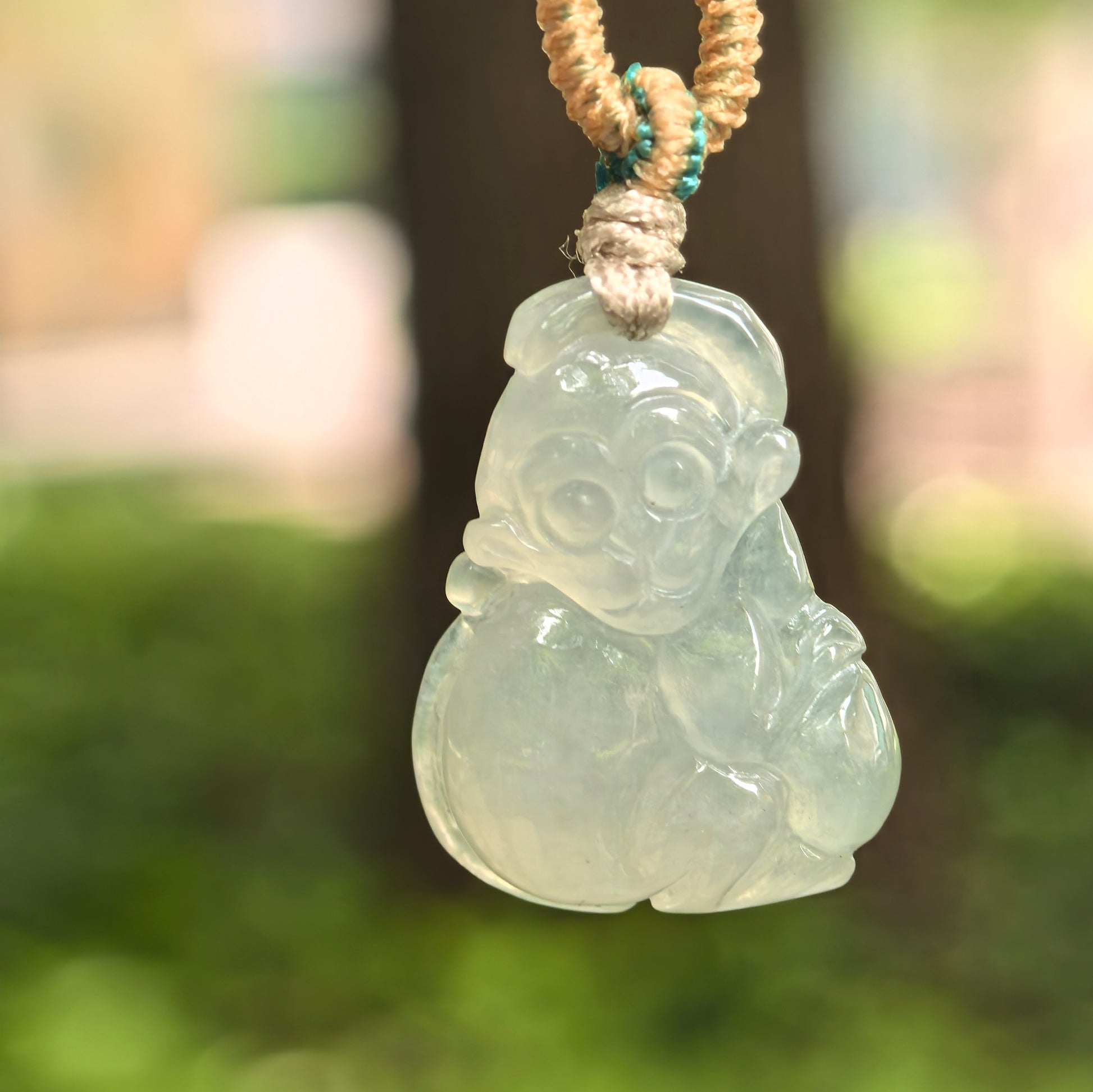 Natural Grade-A icy glutinous light green monkey jadeite pendant hanging on cord with soft icy-gel translucency.
