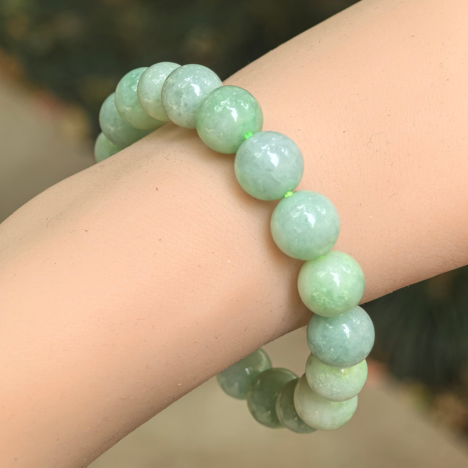 Natural Grade-A apple green jadeite bead bracelet worn on wrist, showing polished round beads and soft glutinous texture.
