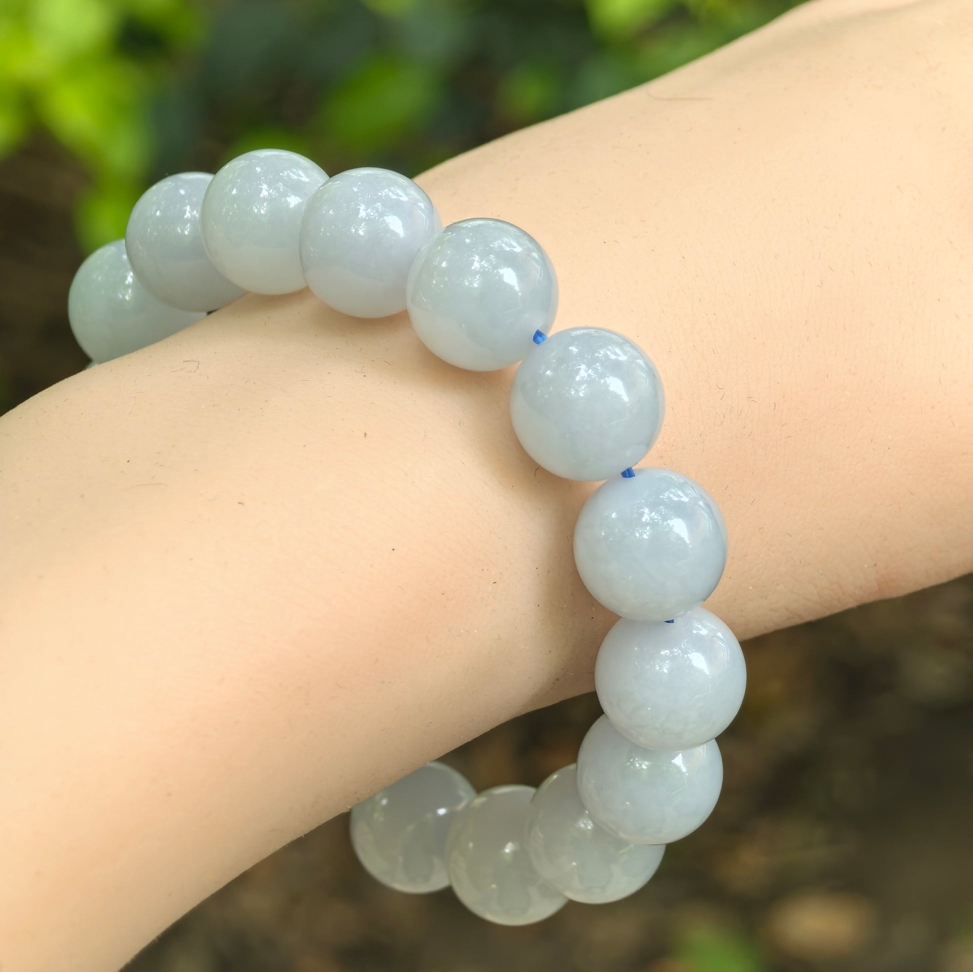 Natural Grade-A fine glutinous blue-lavender jadeite bracelet worn on wrist with glossy round beads.
