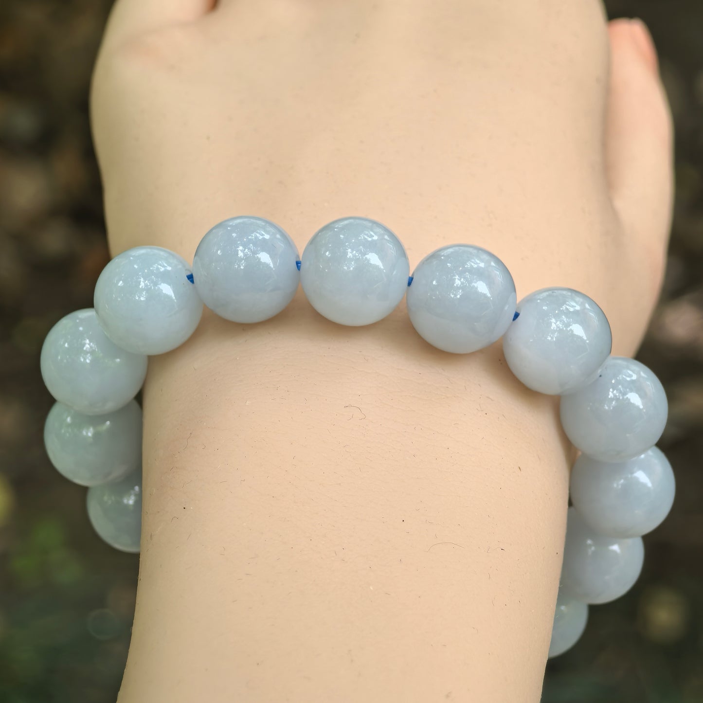 Close-up of blue-lavender round jadeite beads showing fine glutinous texture and soft polish.
