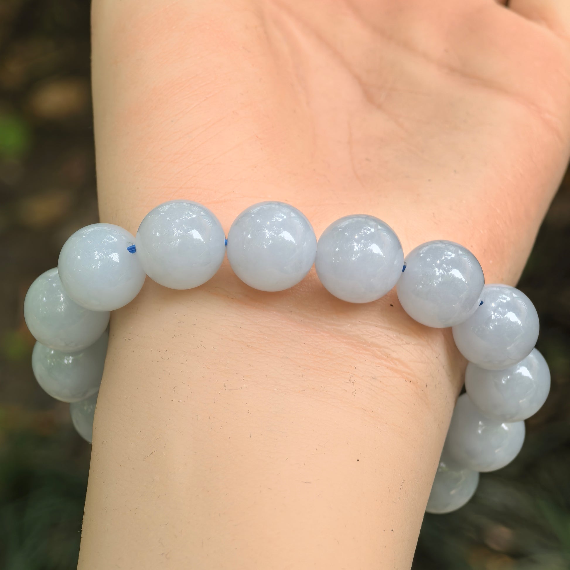 Fine glutinous blue-lavender jadeite bracelet displayed on wrist under natural light.
