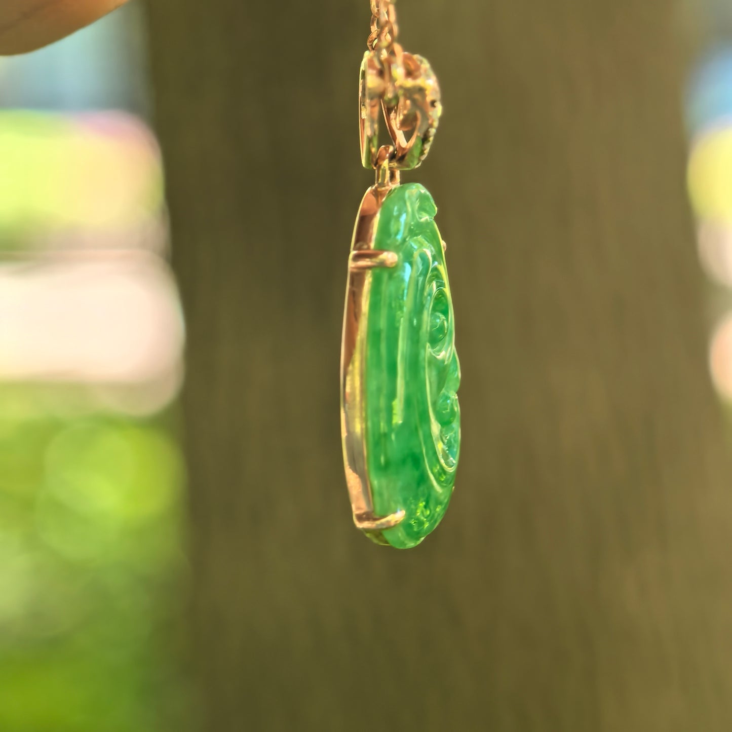 Side view of petite green Ruyi jadeite pendant showing 18K gold setting and slim profile.
