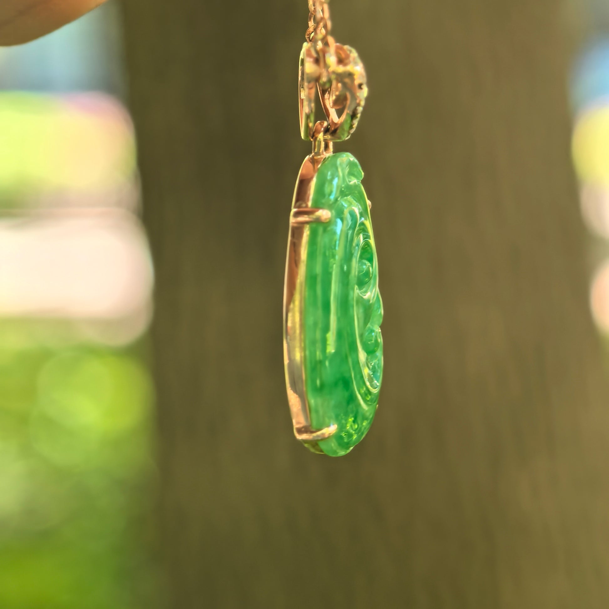 Side view of petite green Ruyi jadeite pendant showing 18K gold setting and slim profile.
