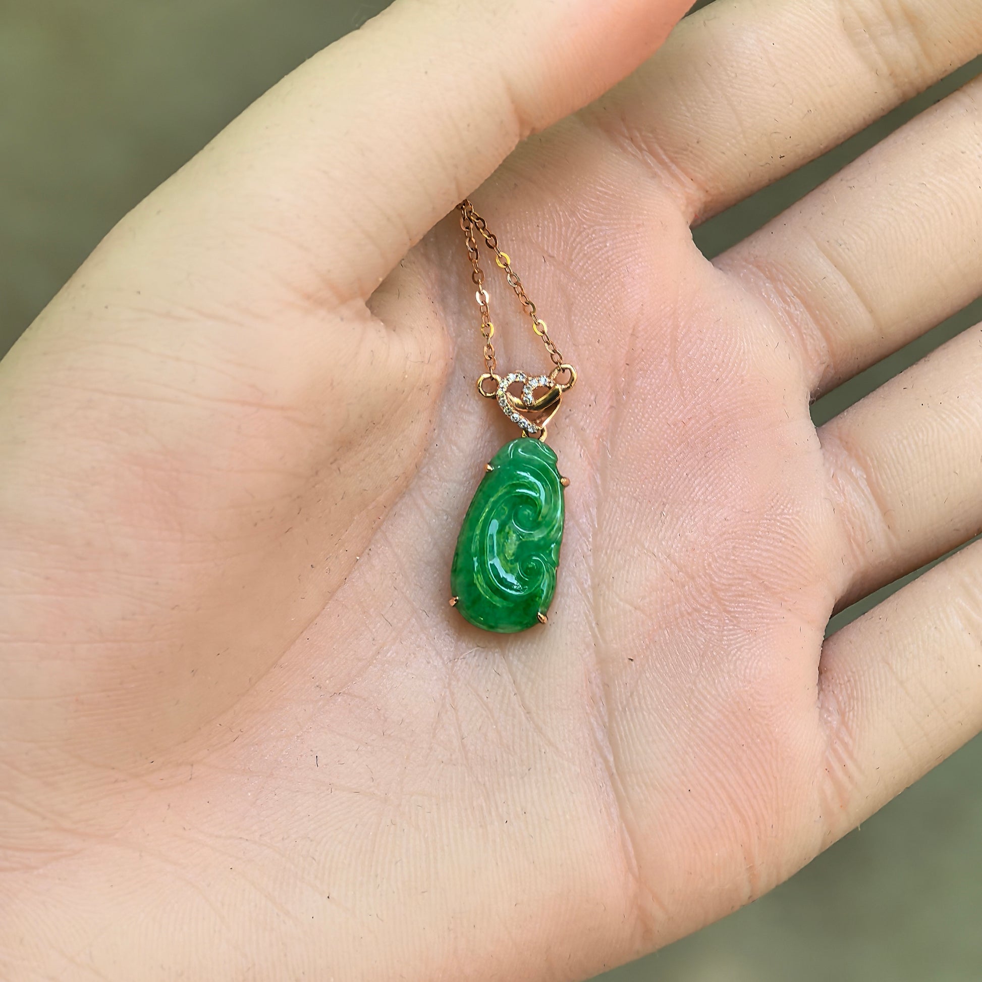 Close-up of glutinous green Ruyi jadeite pendant showing vivid color and smooth carving.