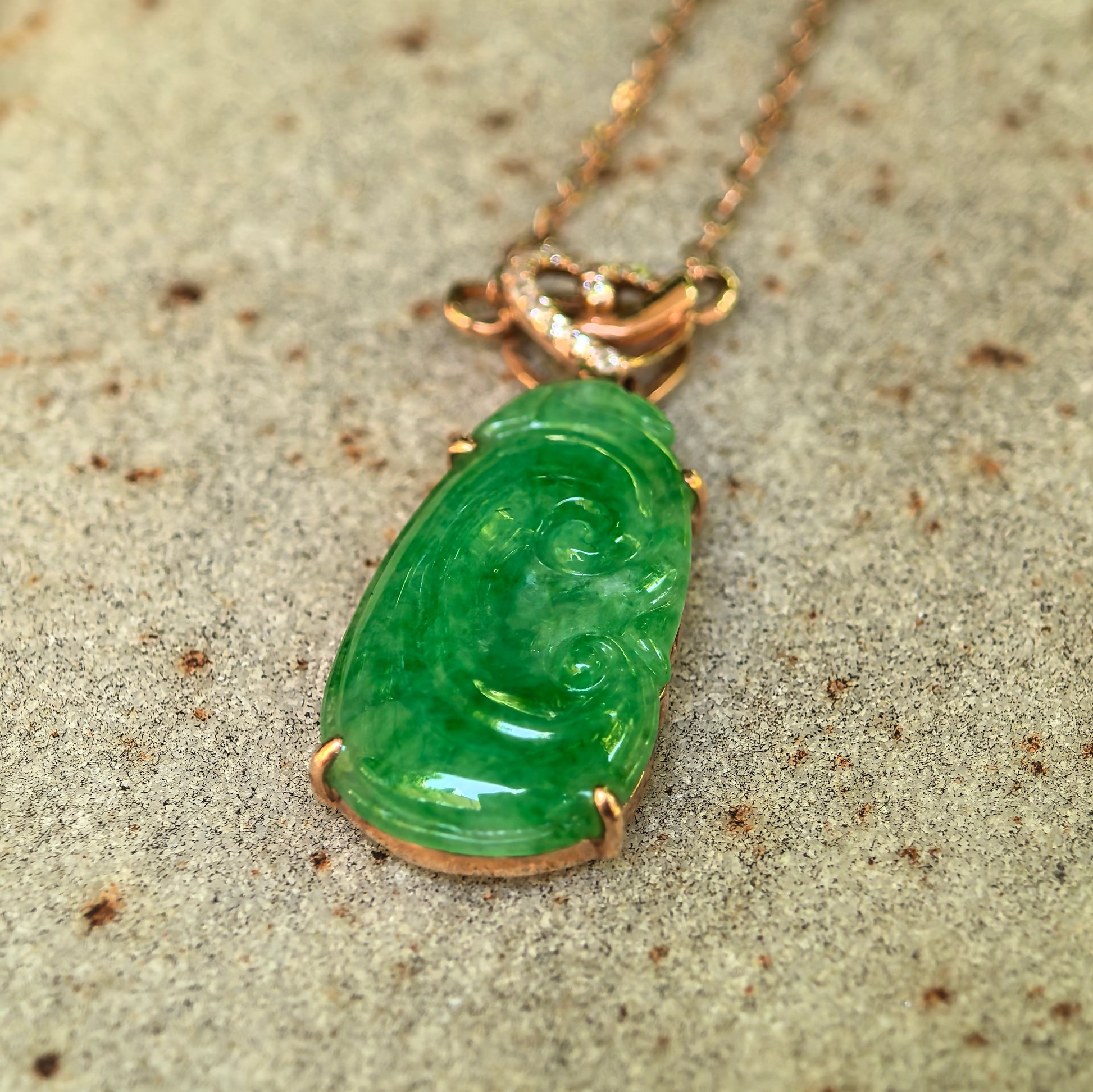 Detailed view of 18K gold set green Ruyi jadeite pendant with polished surface texture.