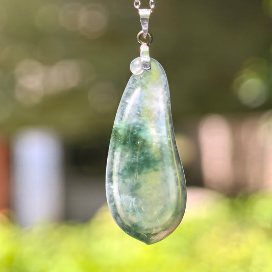 Natural Grade-A icy floating flower melon jadeite pendant with 18K gold setting hanging in natural light.
