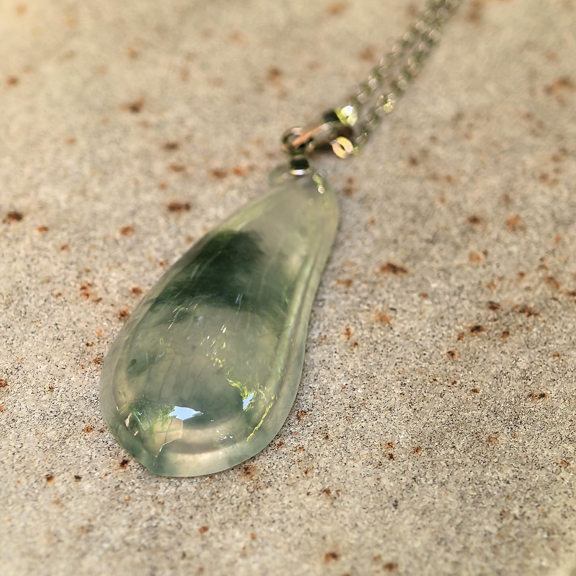 Side view of icy green floating flower melon jadeite pendant showing slim 18K gold mounting.
